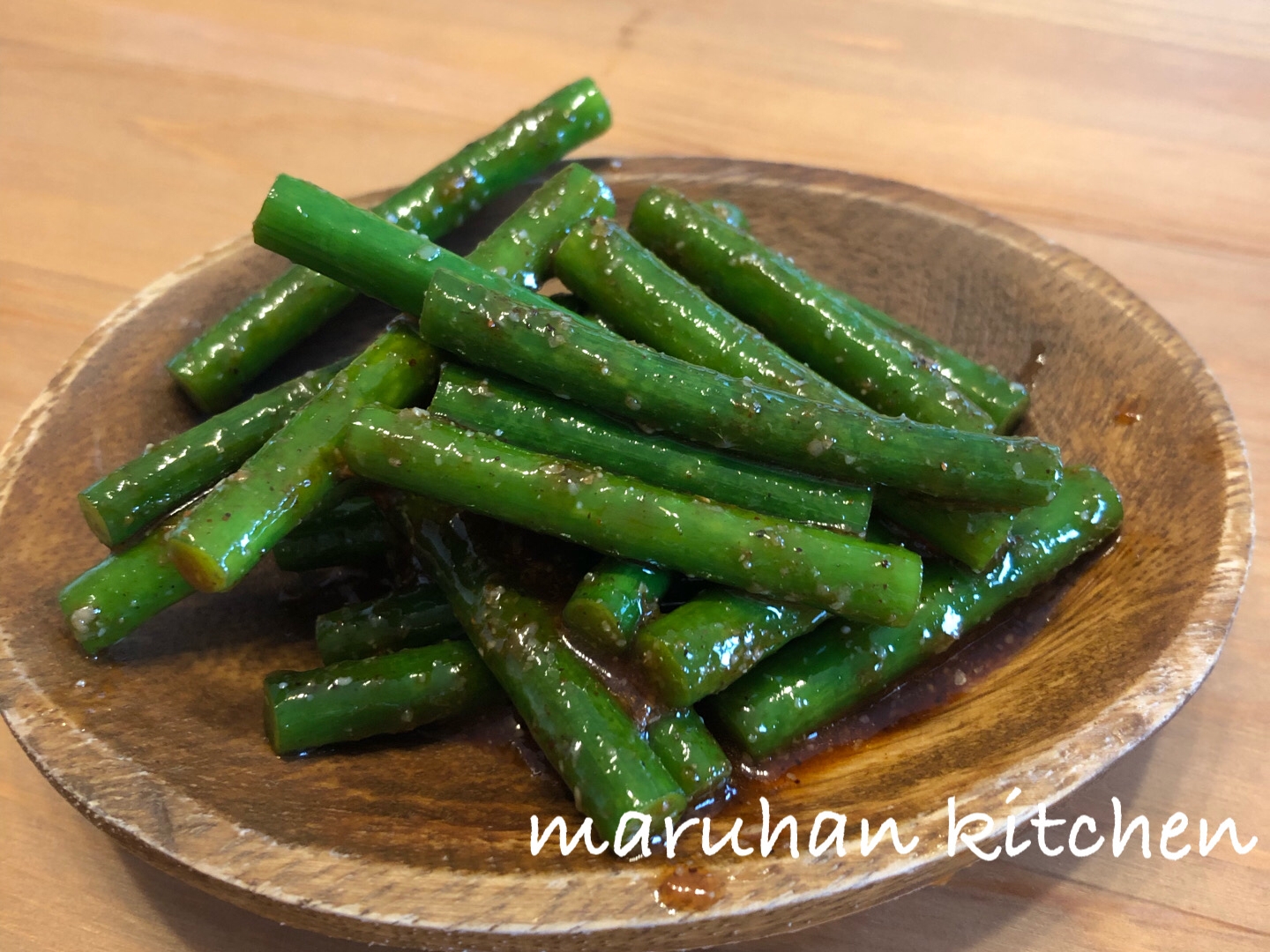 木の皿に盛りつけられたにんにくの芽の旨辛和え