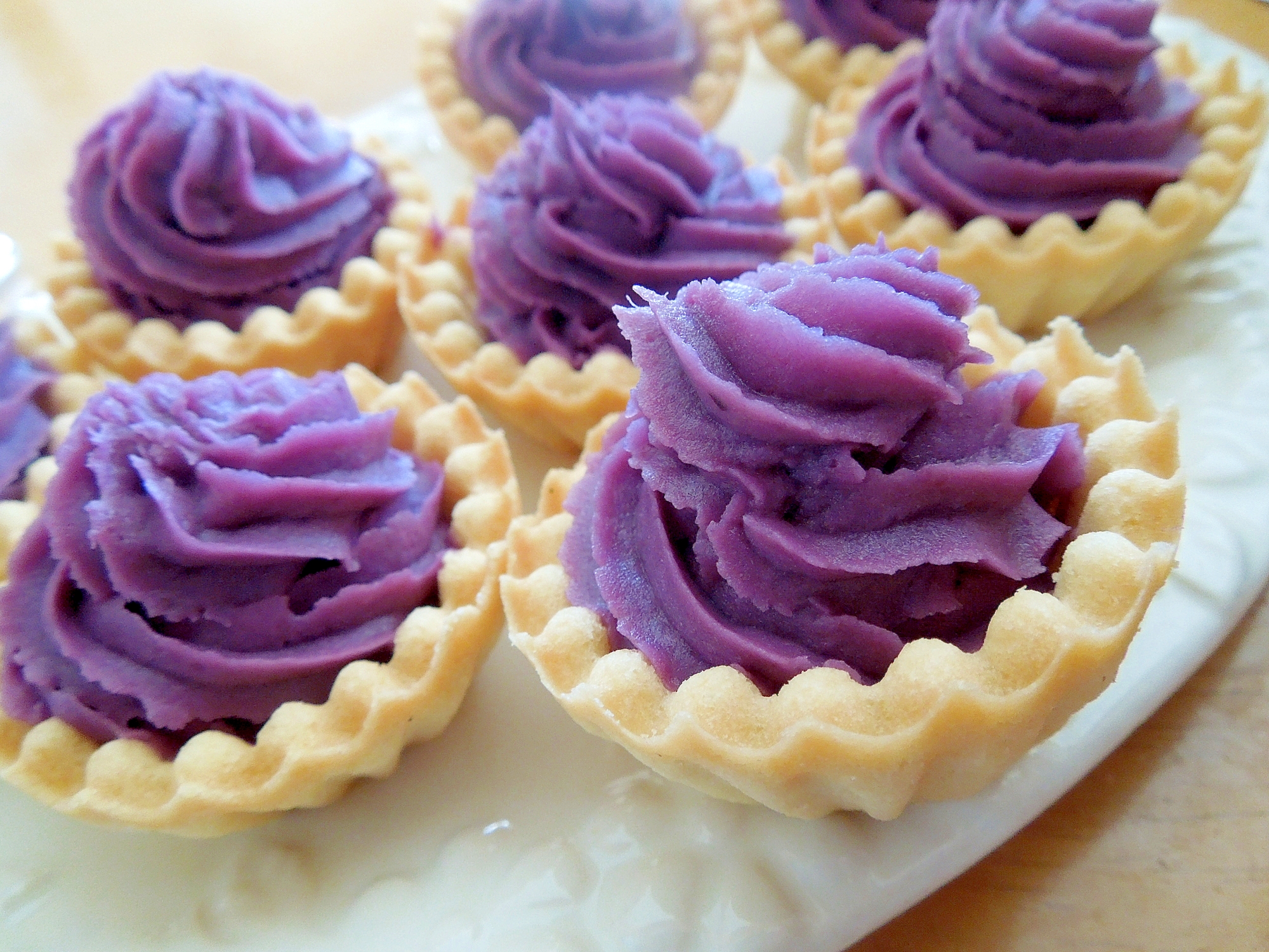 白いプレートのうえに並べたむらさきいものタルト