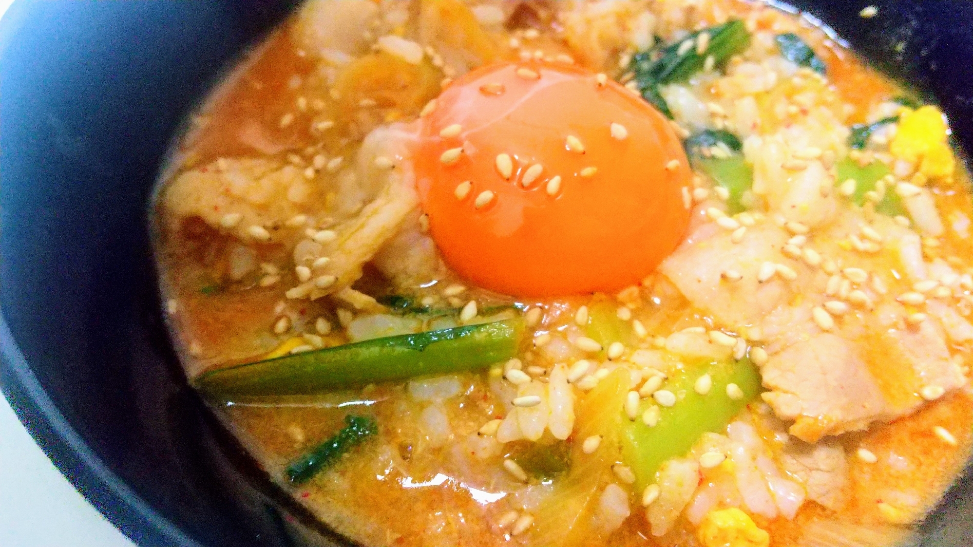 黒い器に盛られた豚キムチ雑炊