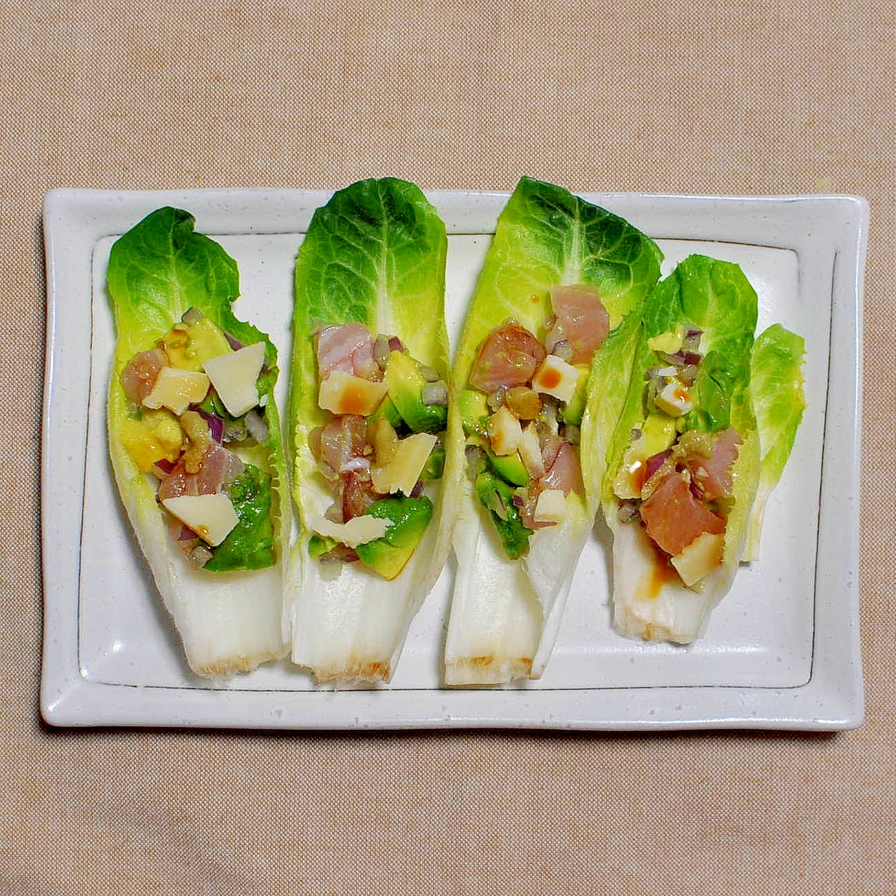 四角い皿に盛られた、生ハムとアスパラガスとチーズのチコリボート