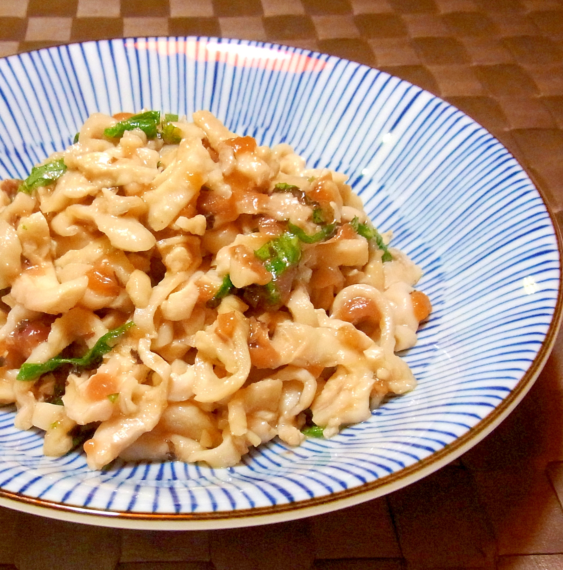 白地に青いストライプ柄の皿に盛られた鶏皮の梅大葉和え