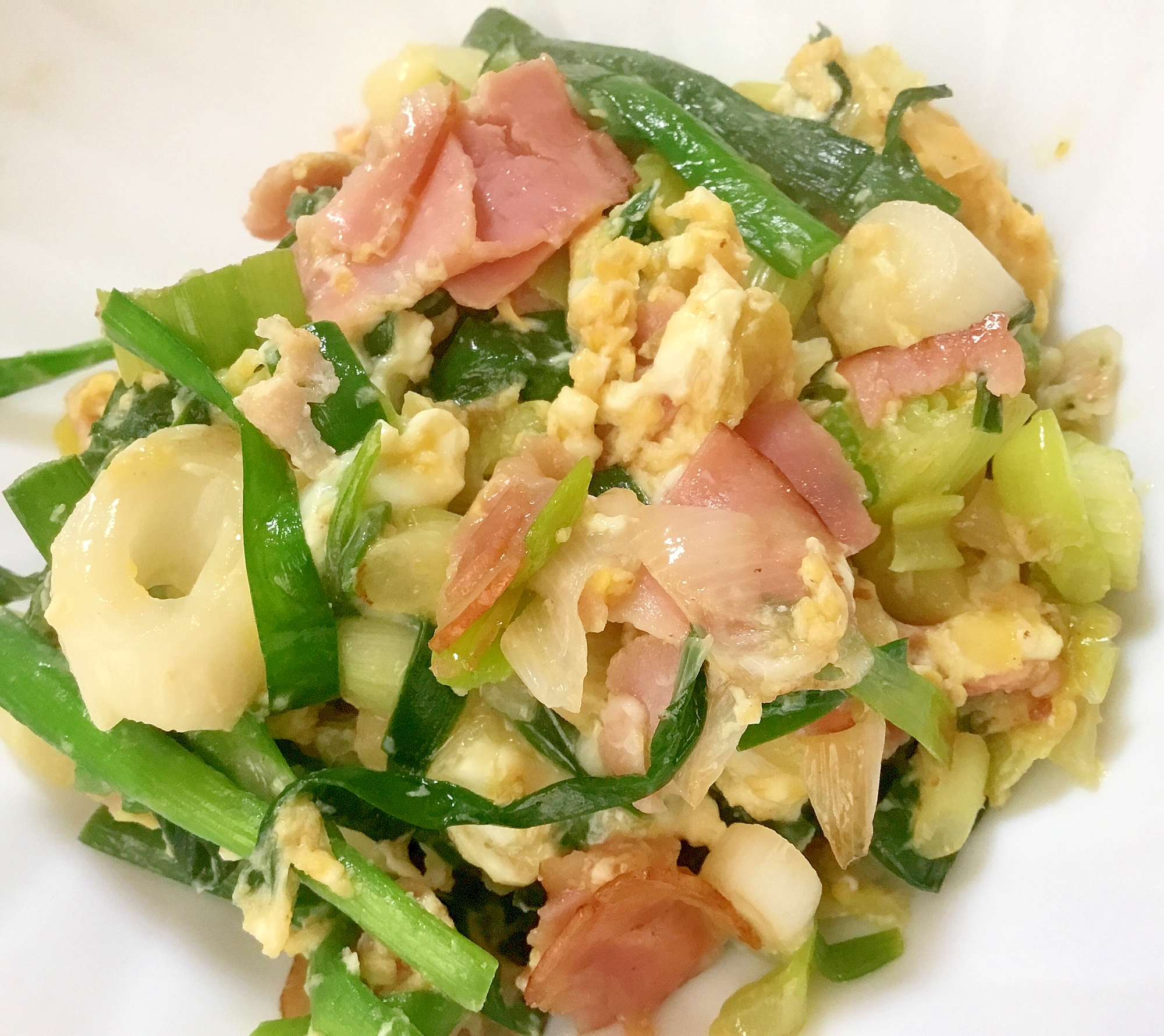 白い皿に盛られた葉玉ねぎとベーコンの炒め物