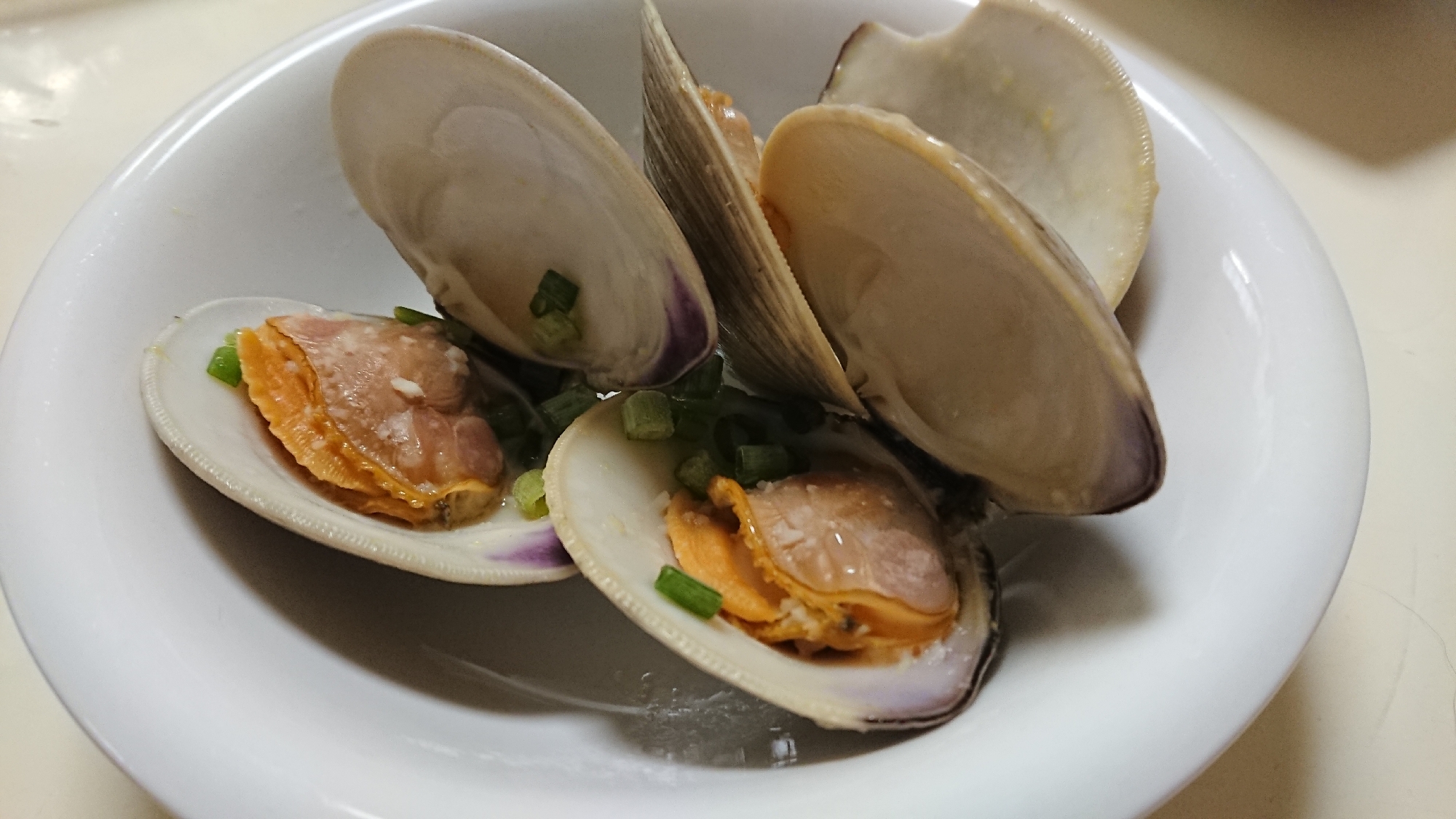 白い皿に盛り付けられたホンビノス貝のバターしょうゆ蒸し