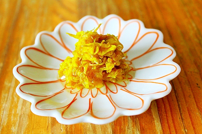赤い縁取りの花型の皿に盛られた食用菊の梅シロップ漬け