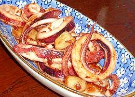 白い小花柄の皿に盛り付けたまるごとにんにくといかの炒め物