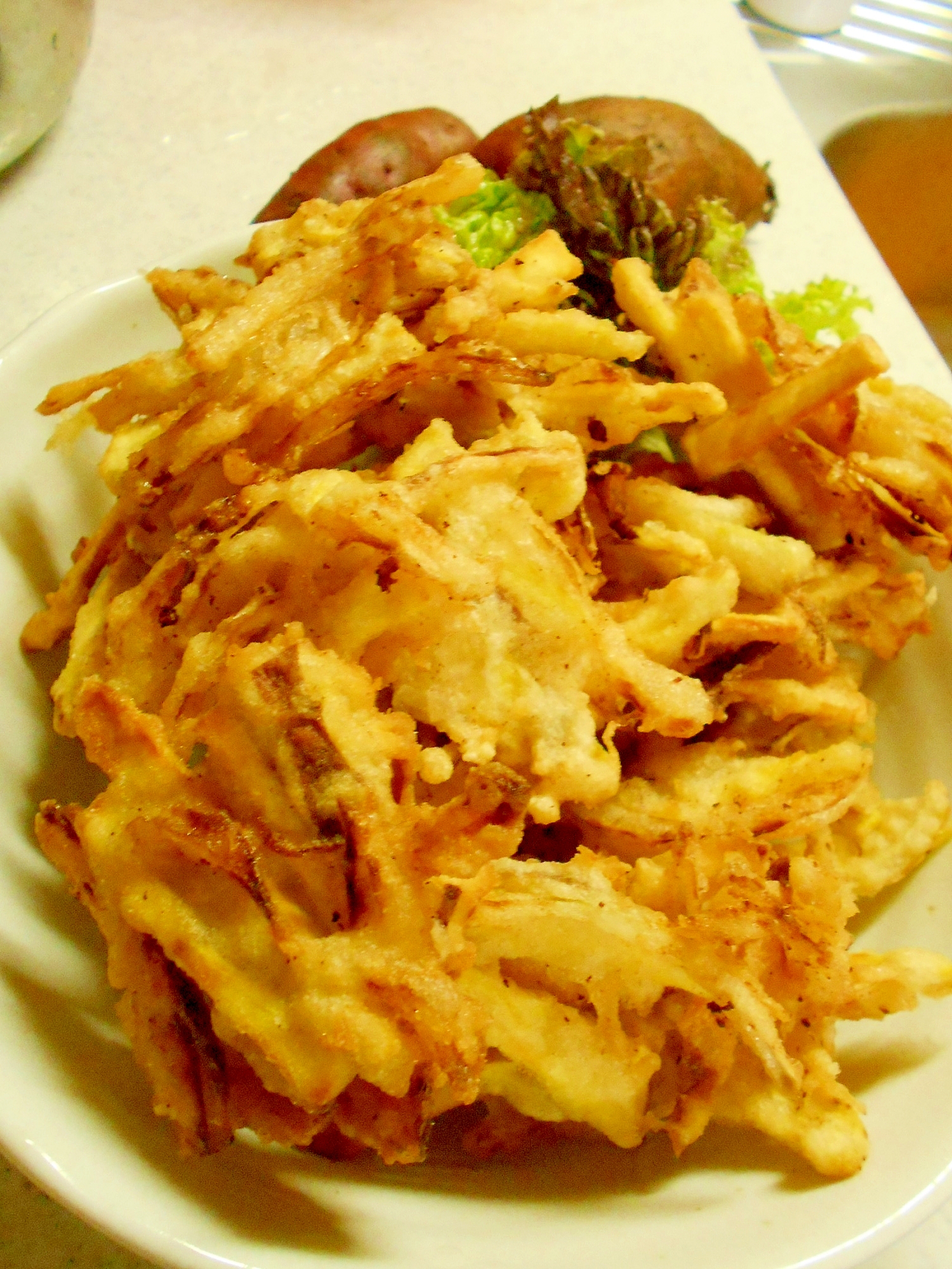 白色の皿に盛られた玉ねぎとさつまいものかき揚げ