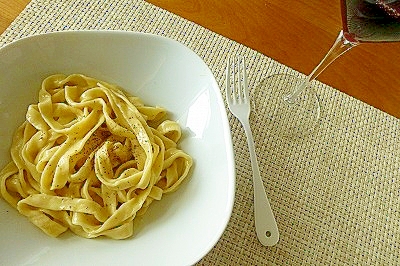 ランチョンマットの上に白い皿に盛りつけられたパスタとフォーク