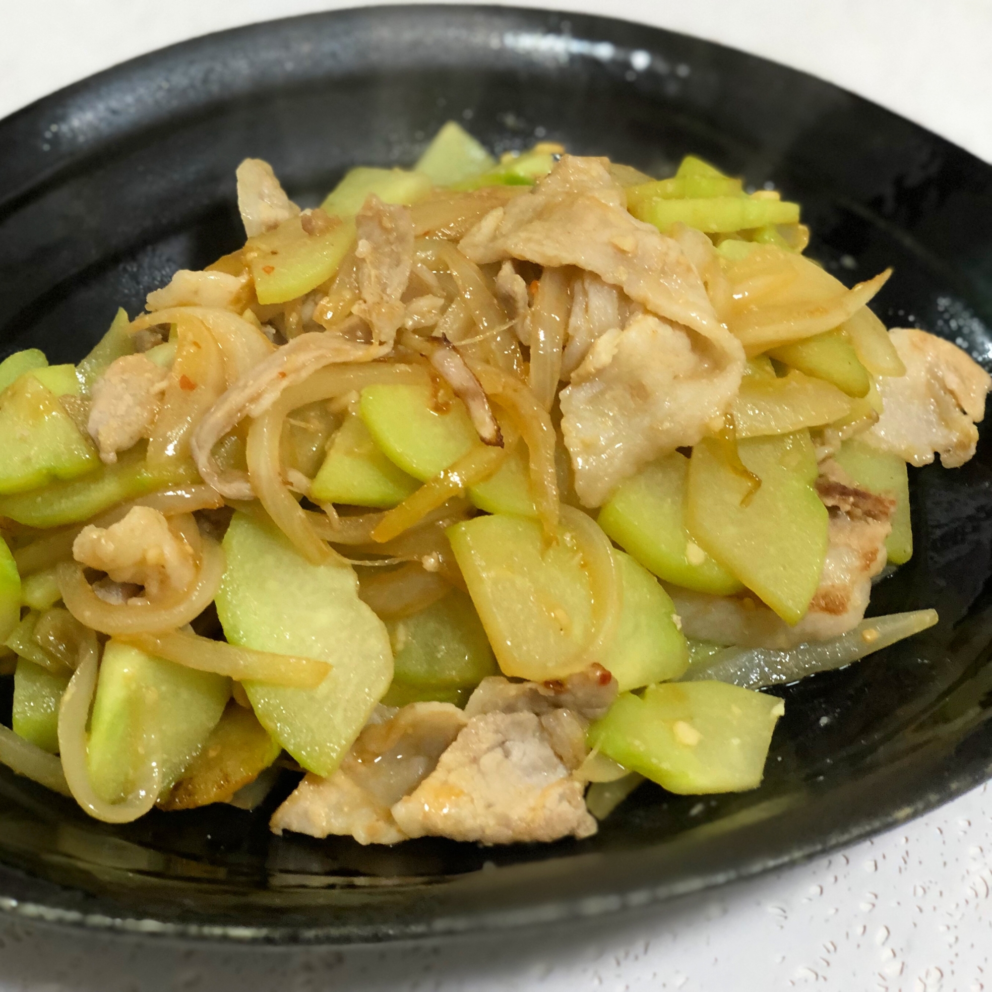 黒い皿に盛られた隼人瓜と豚肉のみそ炒め