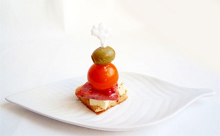 白い皿に盛られたハムとオリーブのピンチョス