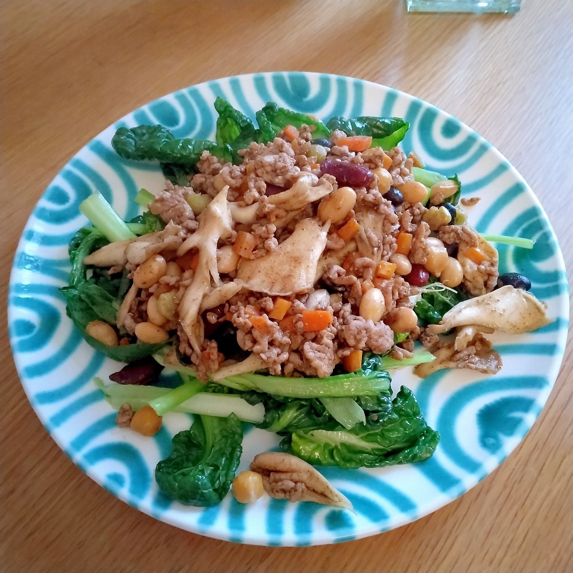 丸い皿に盛り付けられたちぢみほうれん草とドライカレーのサラダ