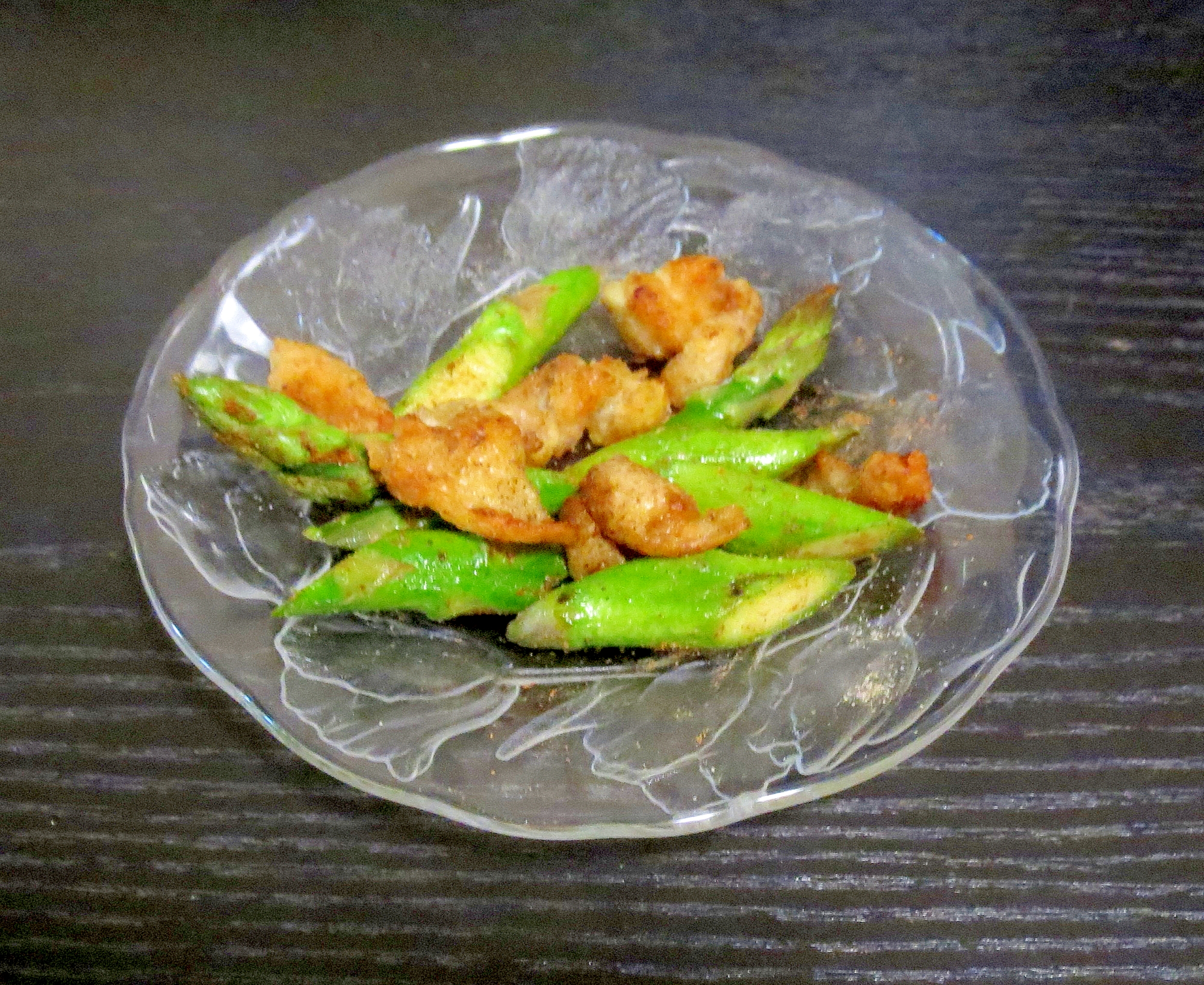 透明な皿に盛られた鶏皮とアスパラガスのカレー炒め