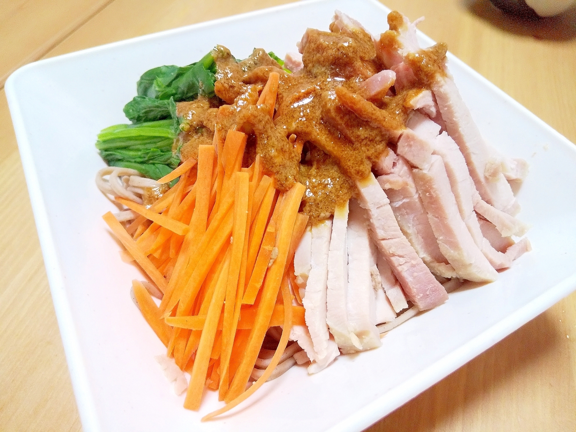 白い皿に盛り付けた豚肉ガーリックごまそばサラダ