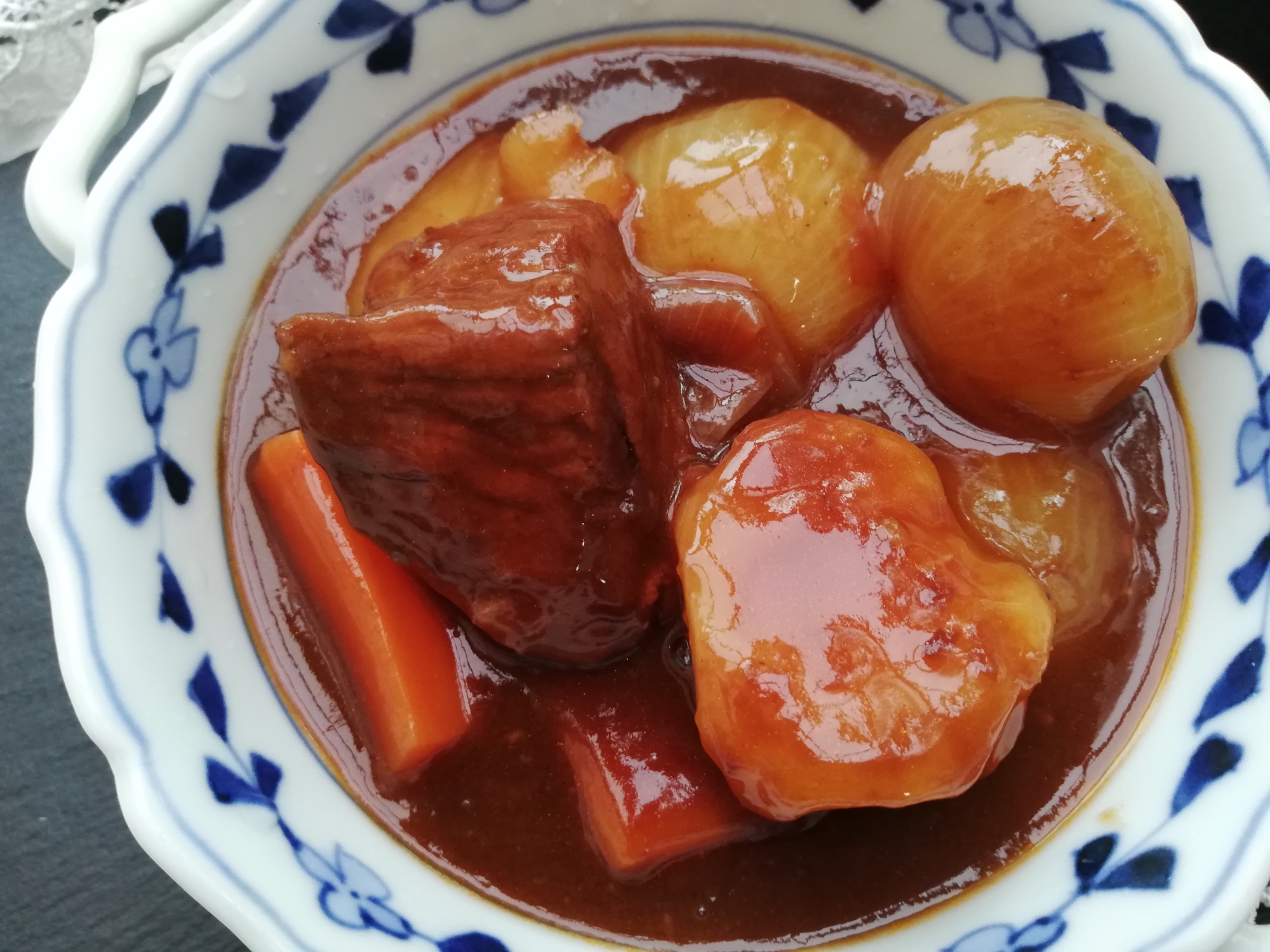 青い花柄が入った白い皿に盛り付けられた牛もも肉のビーフシチュー