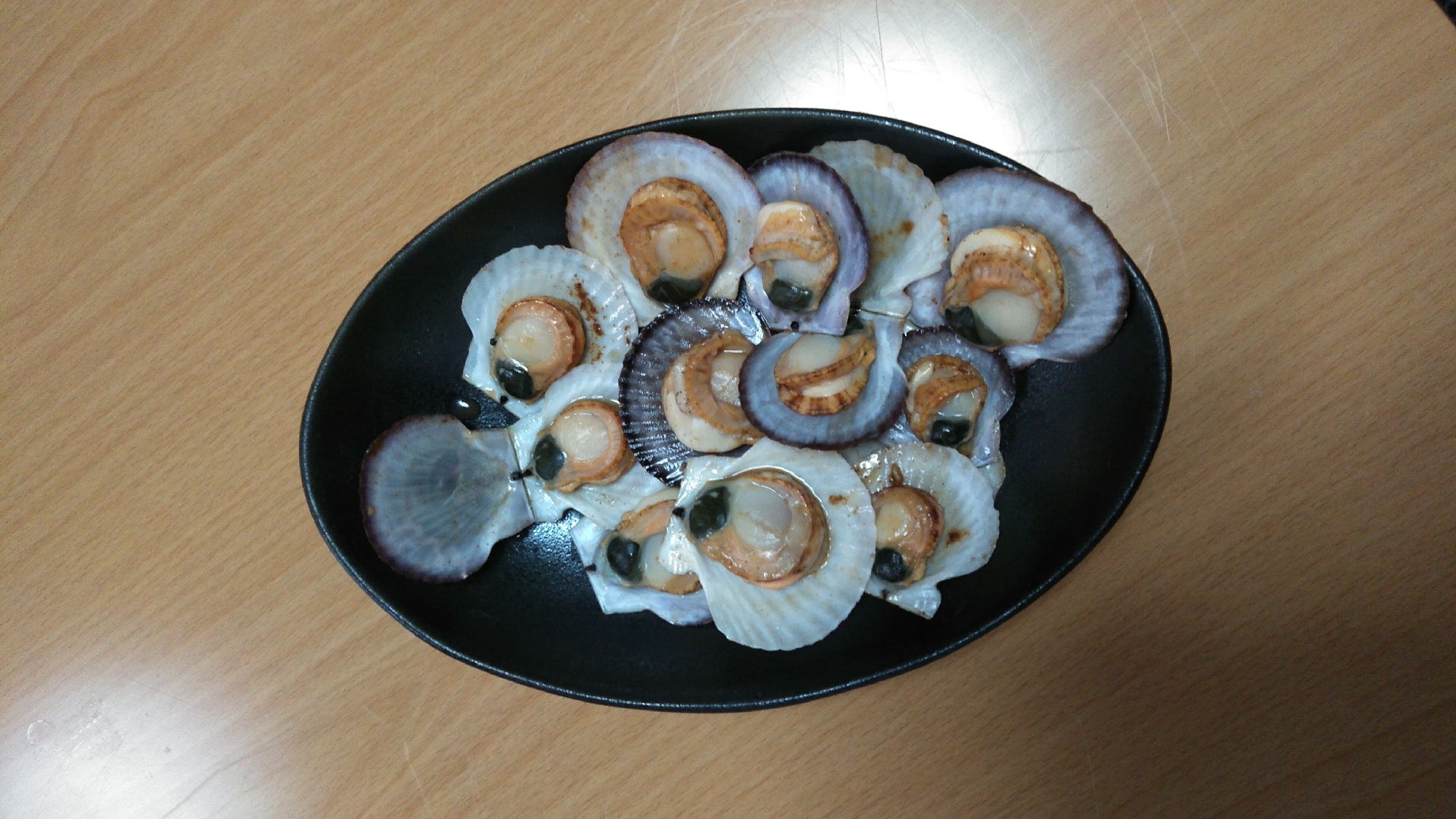 黒い皿に盛り付けたほたてのしょうゆ蒸し