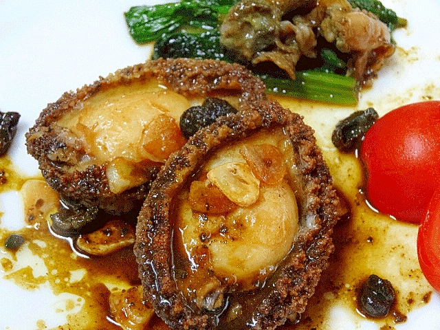 白い器にあわびのステーキや野菜が盛られている