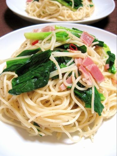 白色の皿に盛られた行者にんにくとベーコンのパスタ