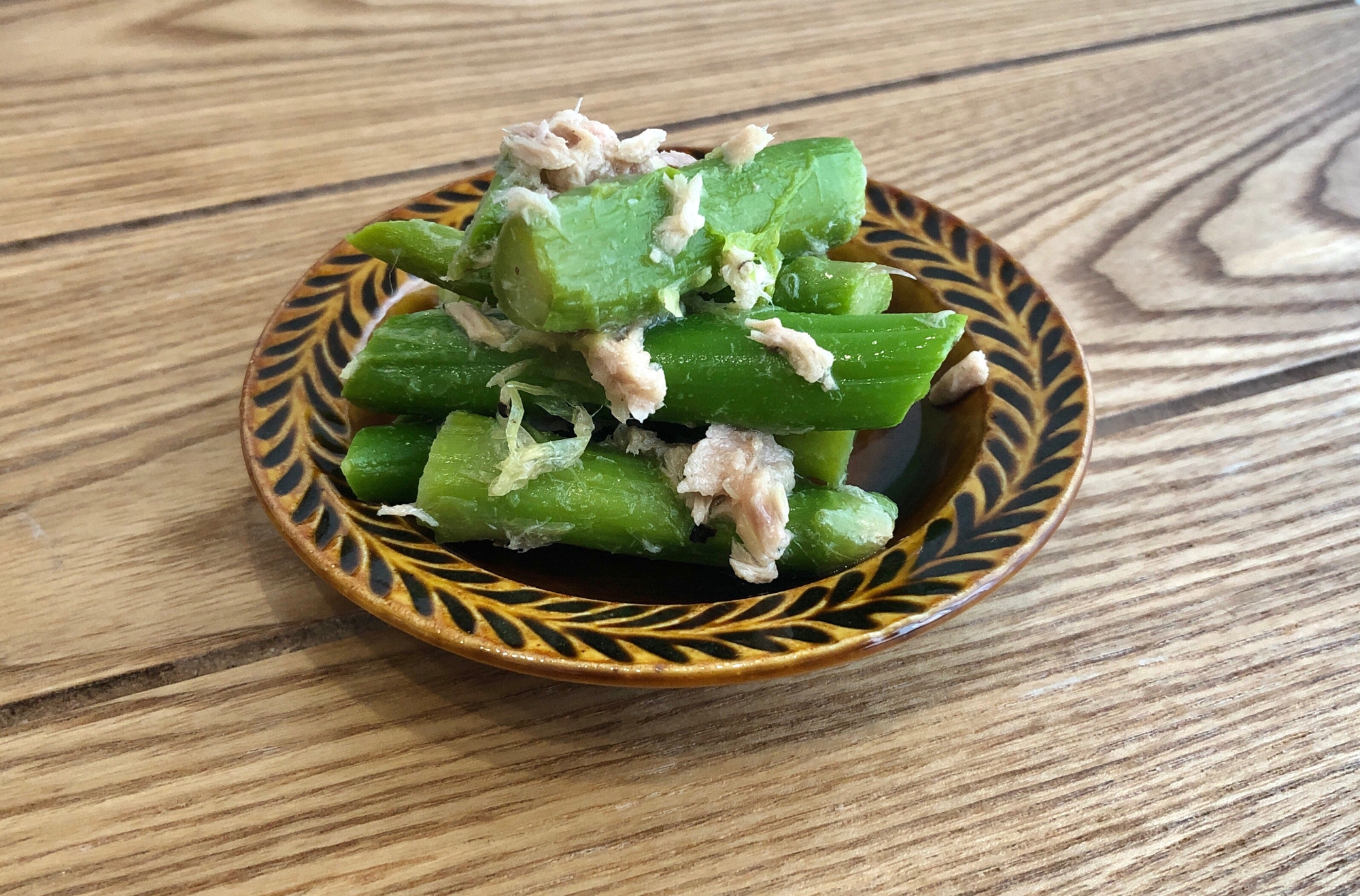 茶色の丸皿に盛られた冷凍アスパラとツナのレモンマリネ