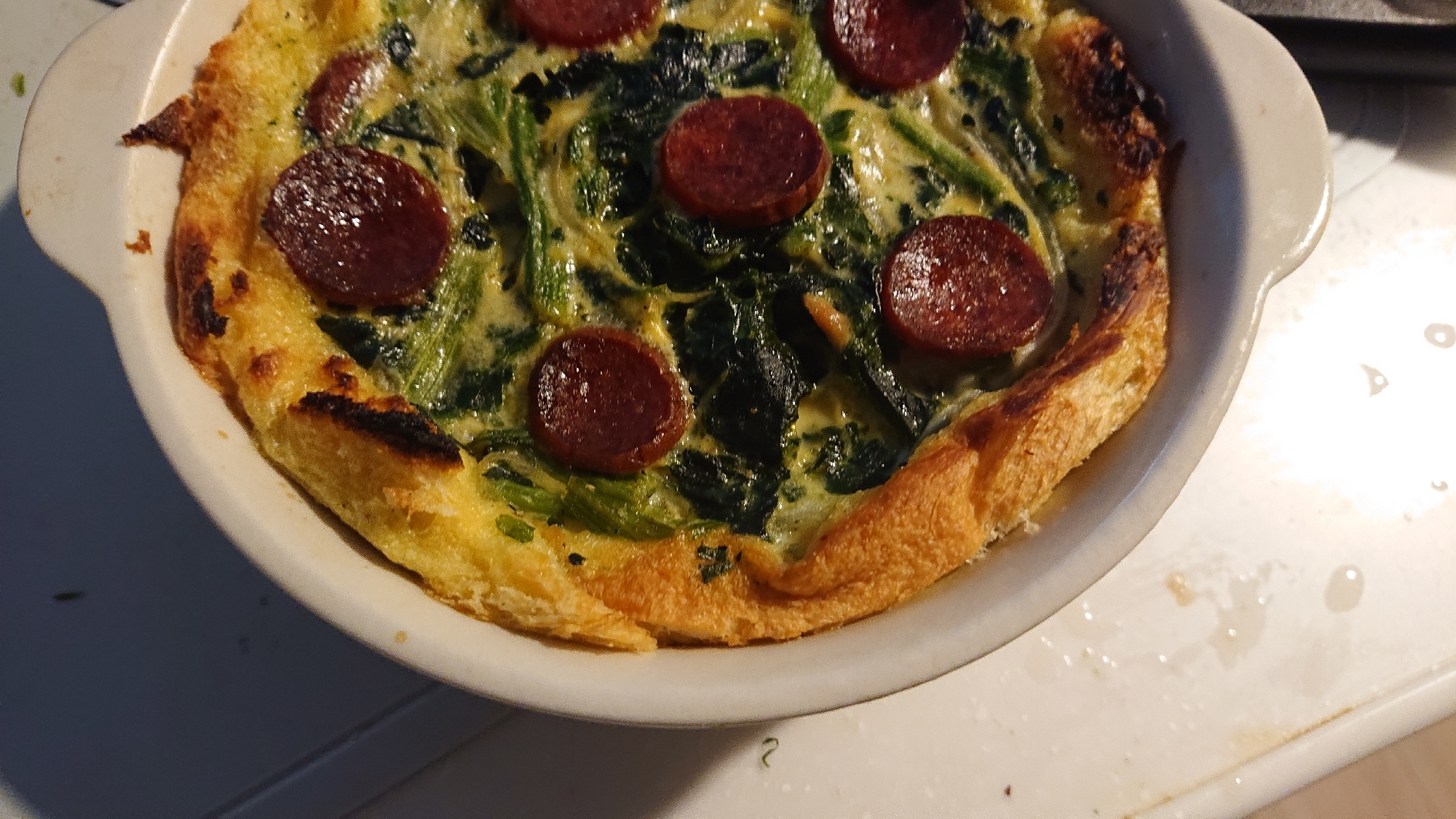 白いグラタン器に入ったほうれん草サラミのキッシュ