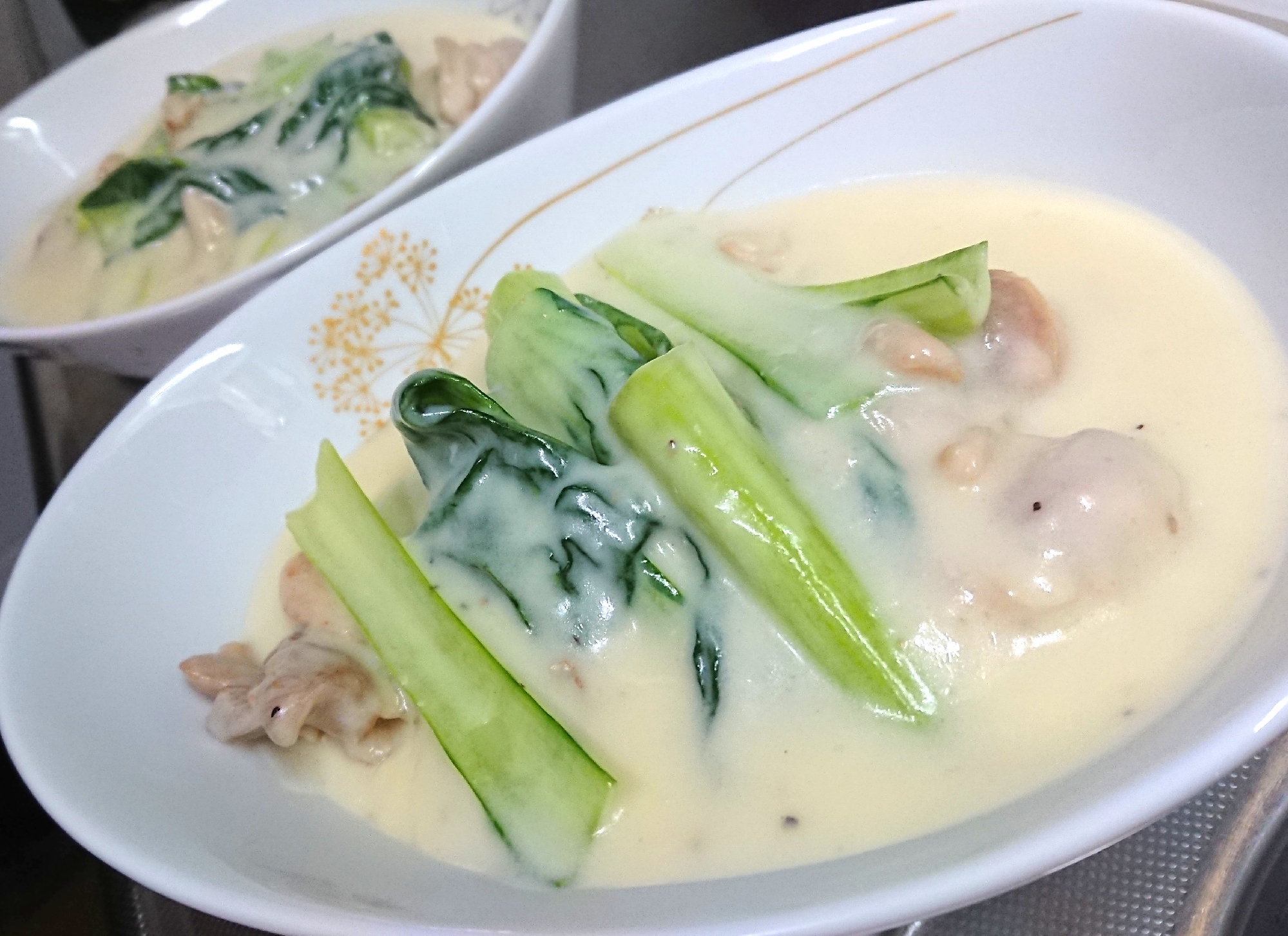 白い皿に盛り付けられたターサイと鶏肉のクリーム煮