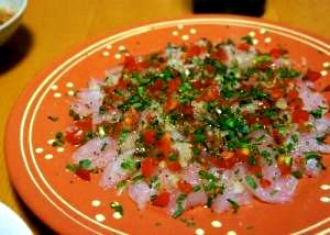 オレンジのお皿に盛り付けられた白身魚のカルパッチョ