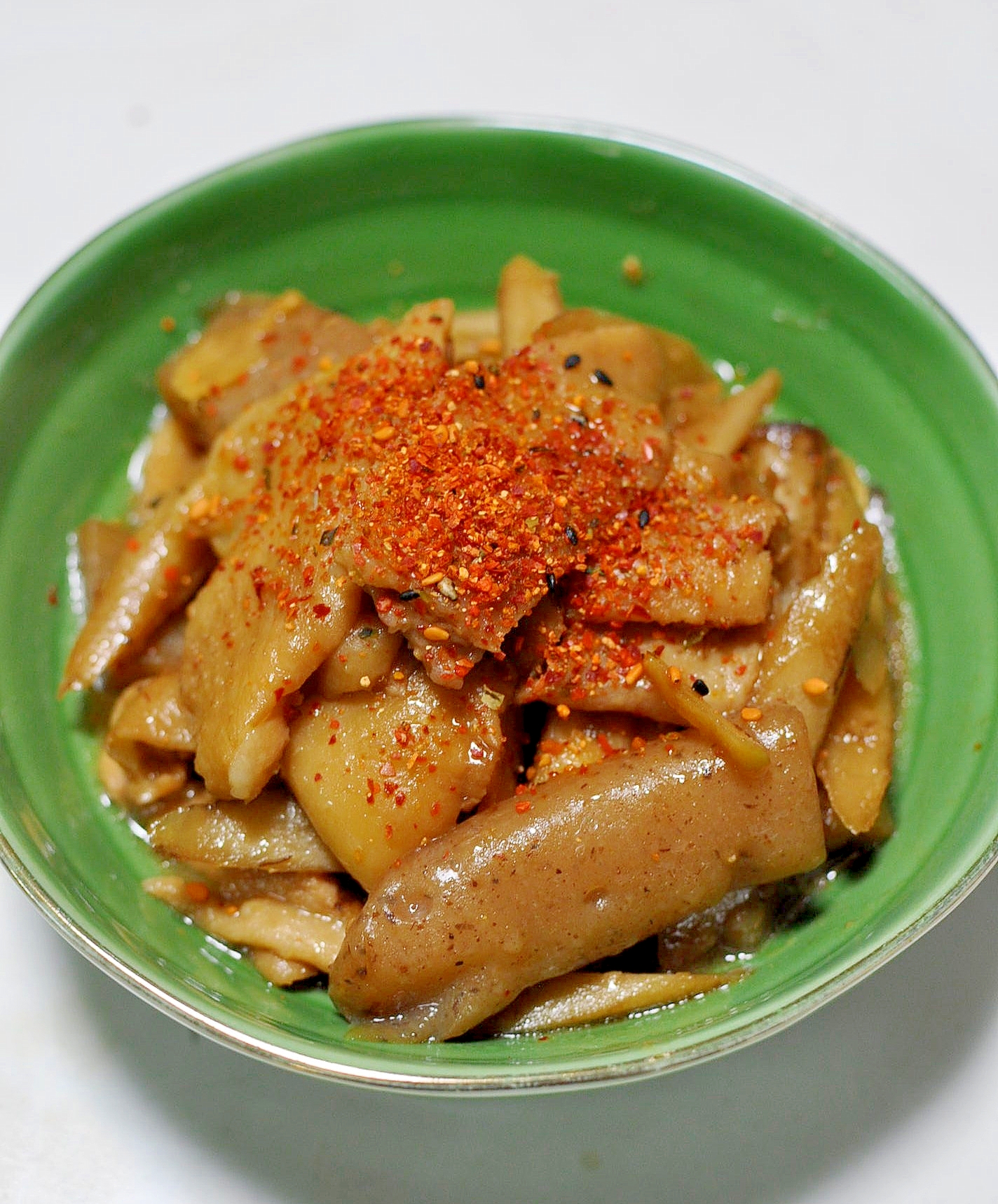 緑色の皿に盛られた鶏皮とごぼうとこんにゃくのみそ煮込み