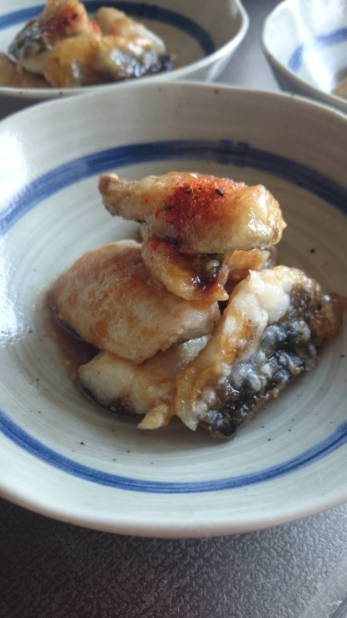 青いライン入りの丸皿に盛り付けたトビウオの甘辛揚げ