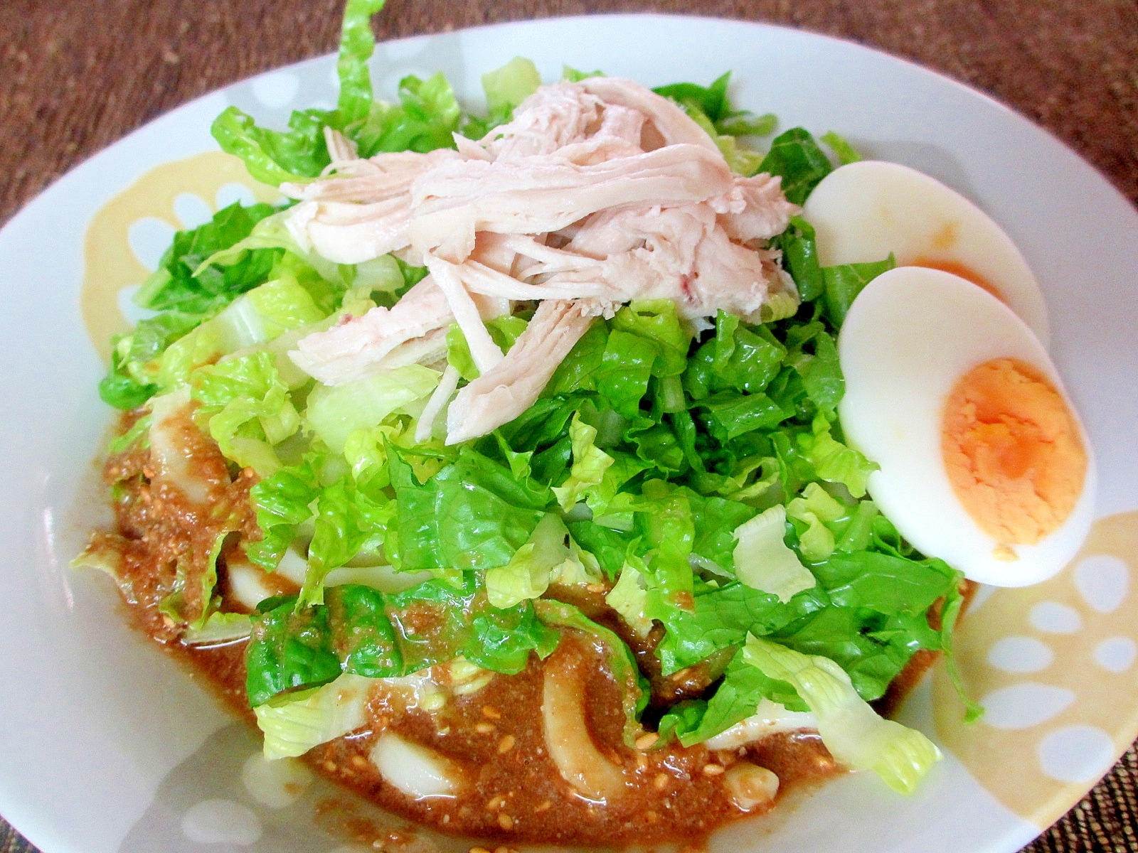 白い皿に盛り付けた蒸し鶏のごまダレ冷やしうどん