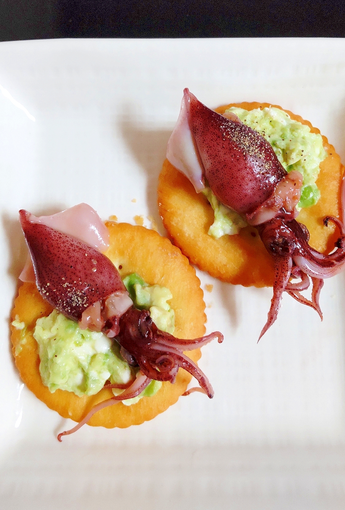 白い皿にのせたホタルイカとアボカドのカナッペ