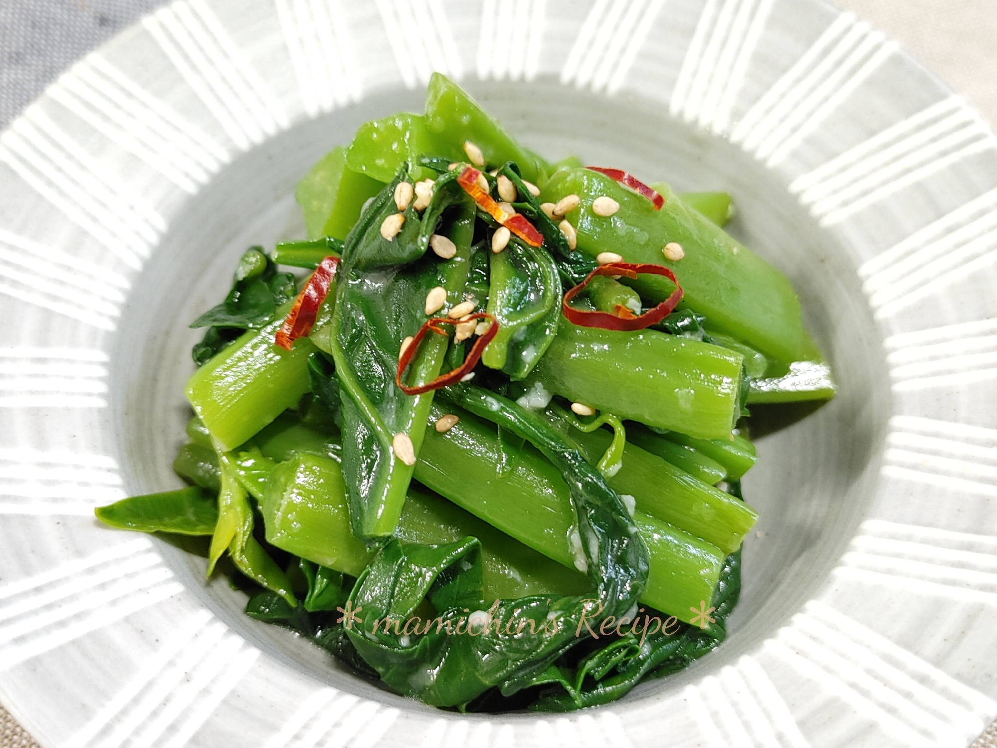 グレーの皿に白い模様が入った皿に盛り付けたツルムラサキのナムル