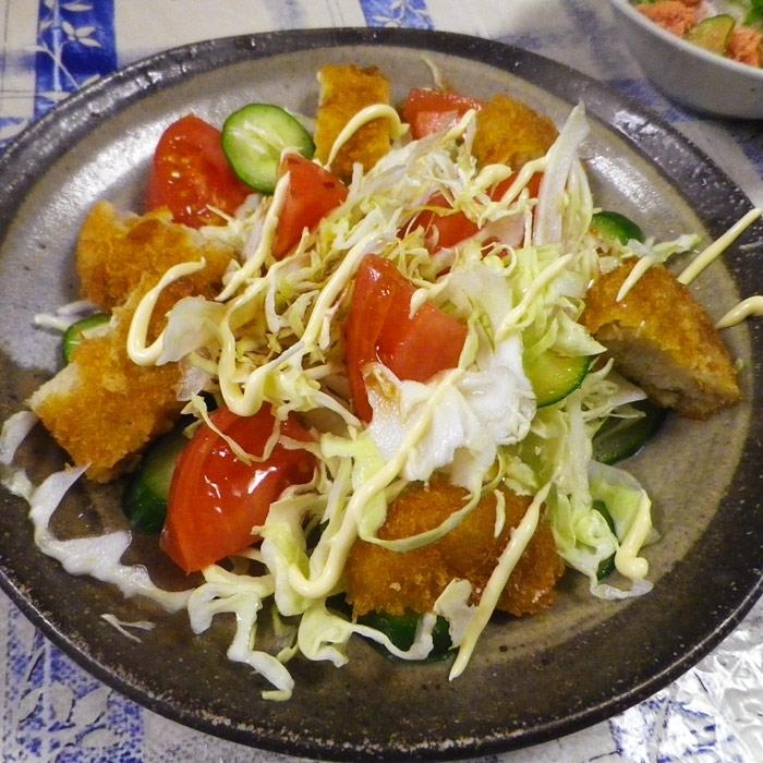 黒い皿に盛られたコロッケのワンプレートサラダ