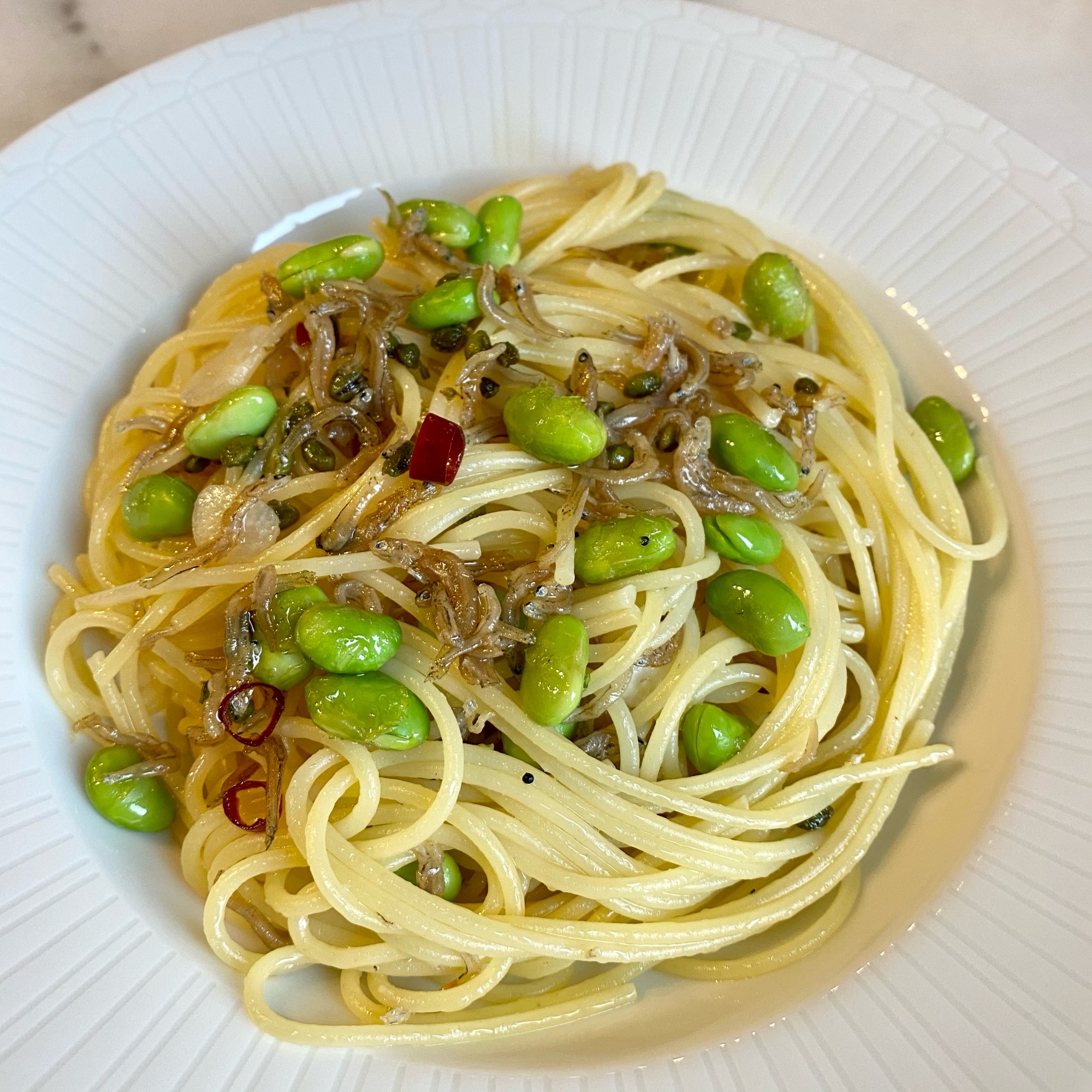 白い皿に盛り付けた枝豆とちりめん山椒のピリ辛ペペロンチーノ