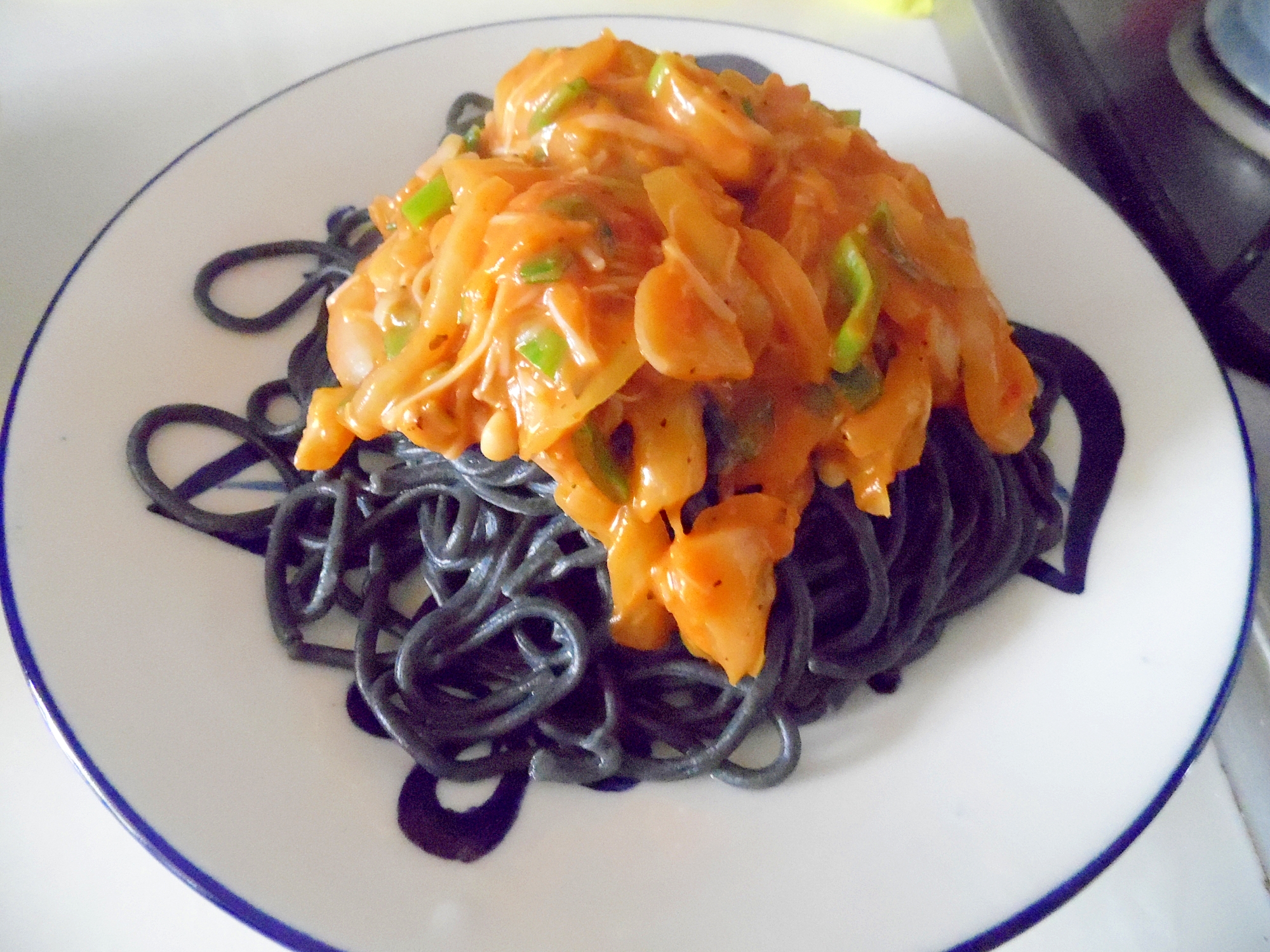 白い皿に盛られた、トマトクリーム味のイカスミパスタ