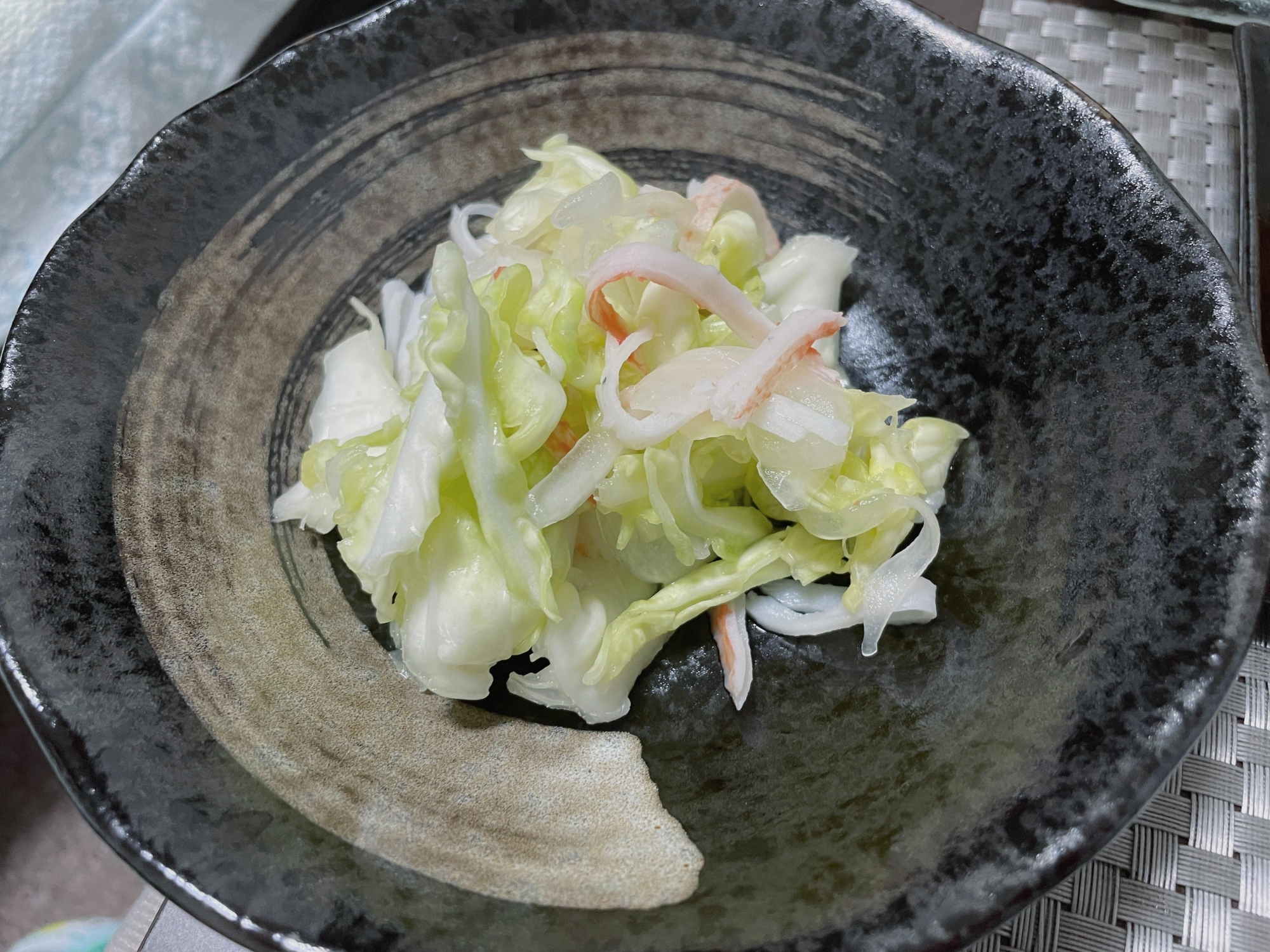 黒いお皿に盛り付けられたキャベツとたまねぎとカニ風味かまぼこのエスニックサラダ