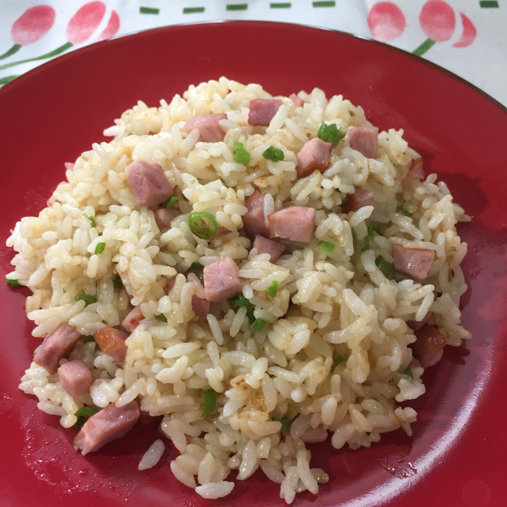 赤い皿に盛り付けた青唐辛子とハムのチャーハン