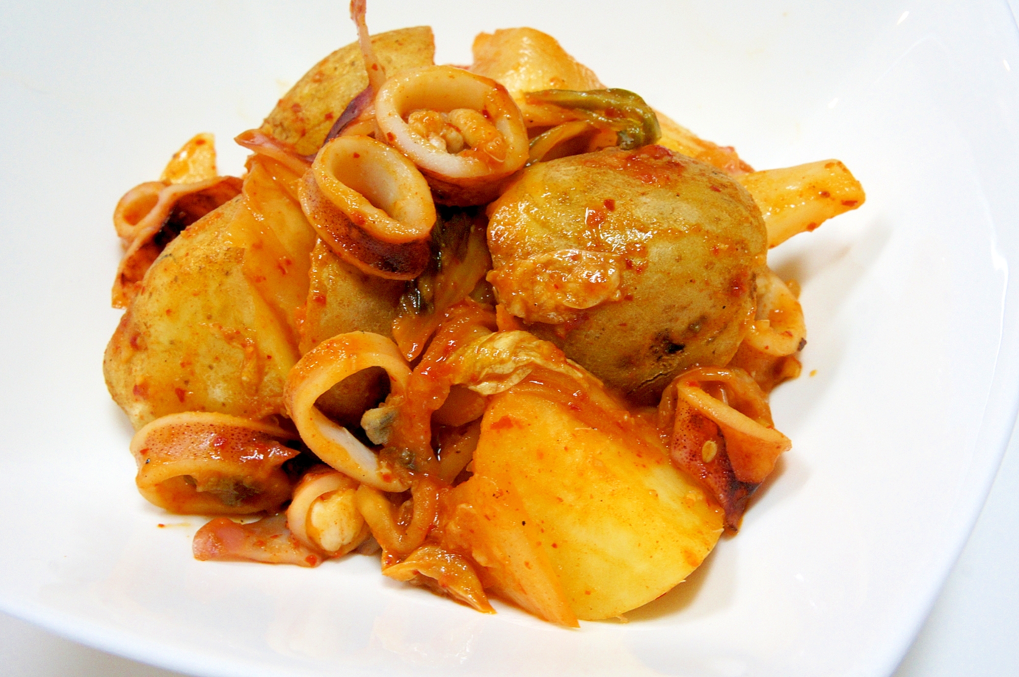 白い皿に入ったヤリイカとじゃがいものキムチ炒め