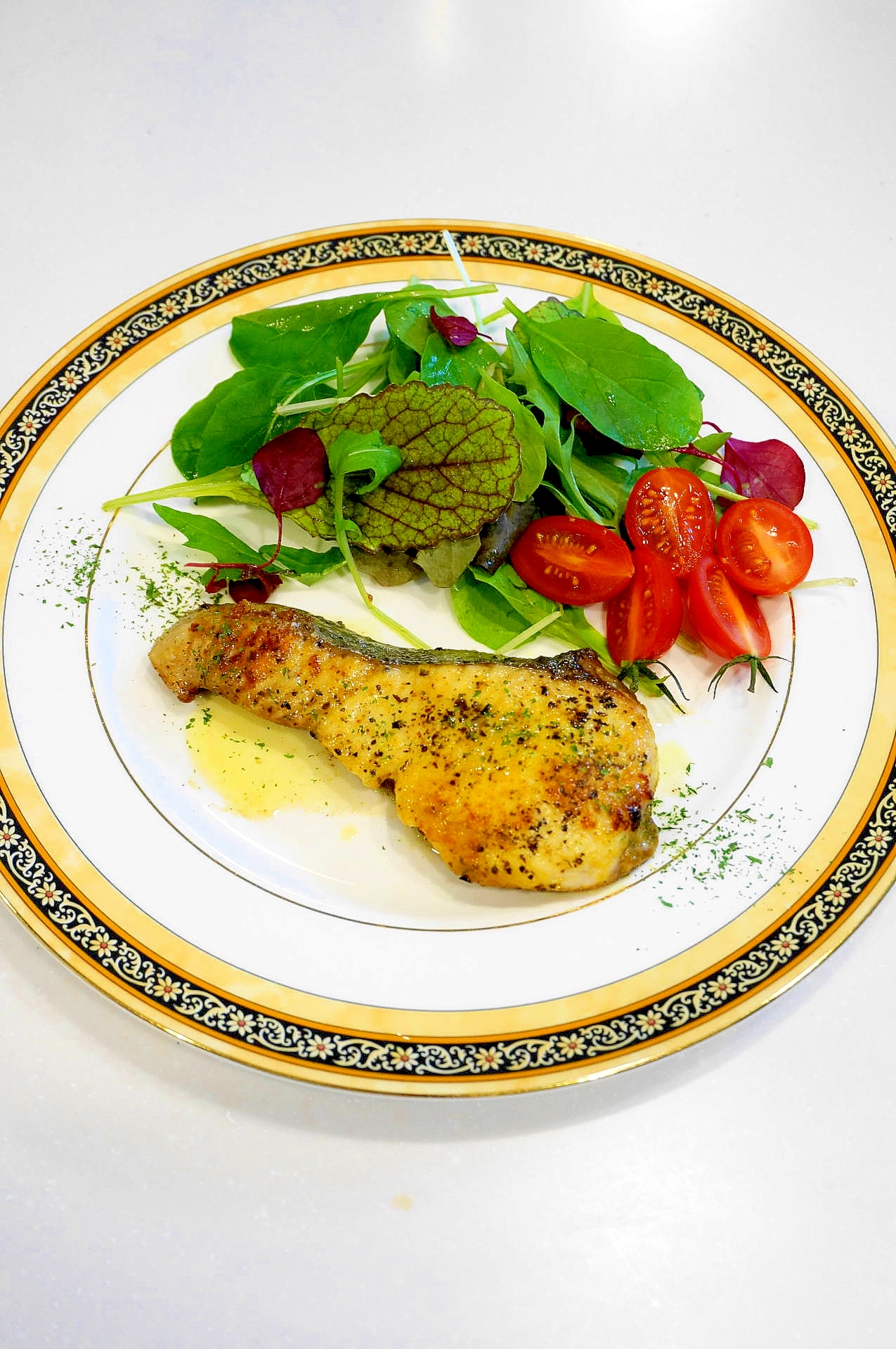 花柄の縁の皿に盛りつけられたさわらのカレームニエル