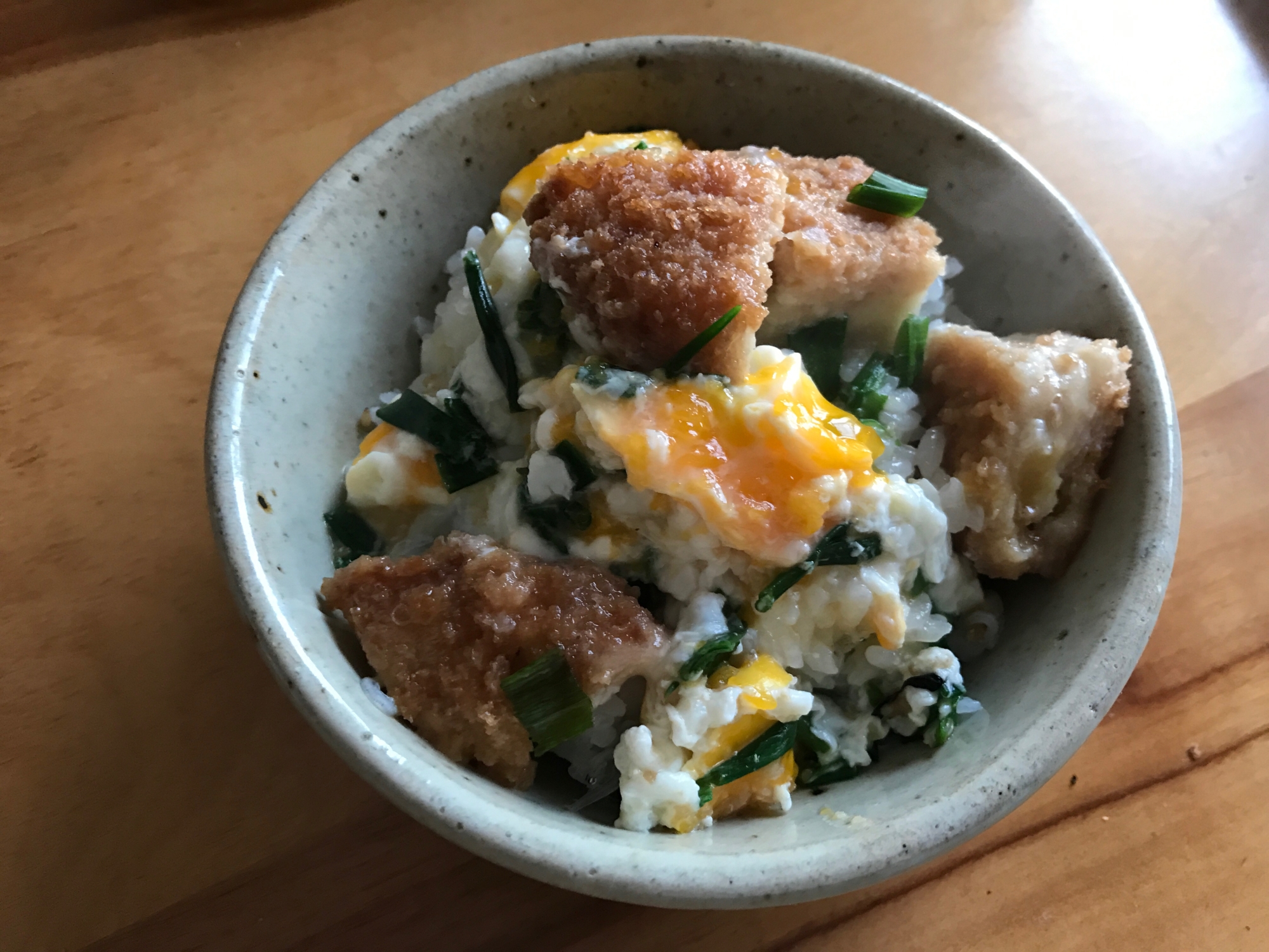 白い器に盛られた長ねぎとコロッケの卵とじ丼