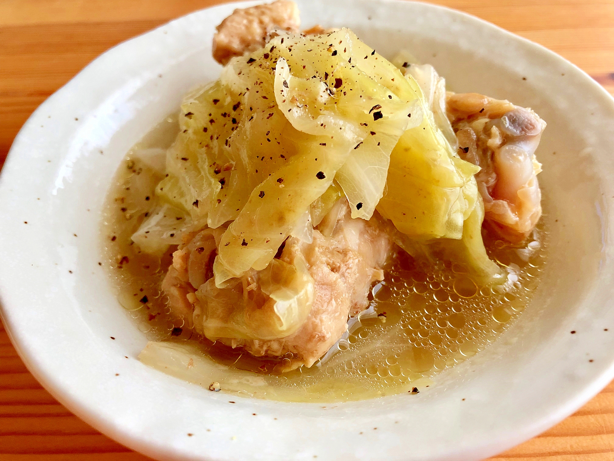 白いお皿に盛り付けられた鶏手羽元とキャベツ、玉ねぎの煮物