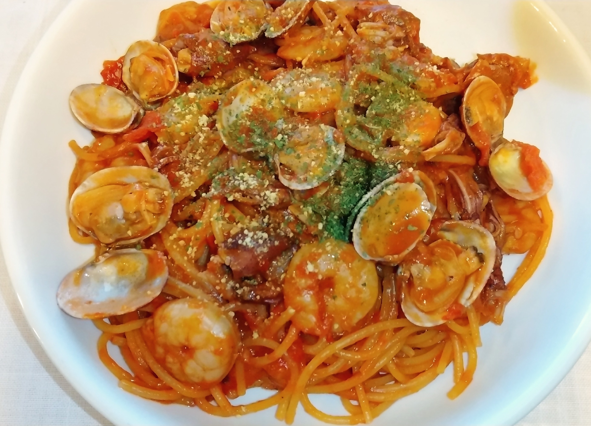 白いお皿に盛り付けられたホタルイカとあさり、むきえびのトマトパスタ