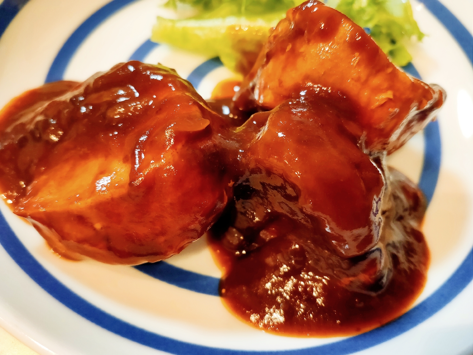 白地に青い模様入りの皿に盛られた豚ヒレ肉のデミグラスソース煮込み