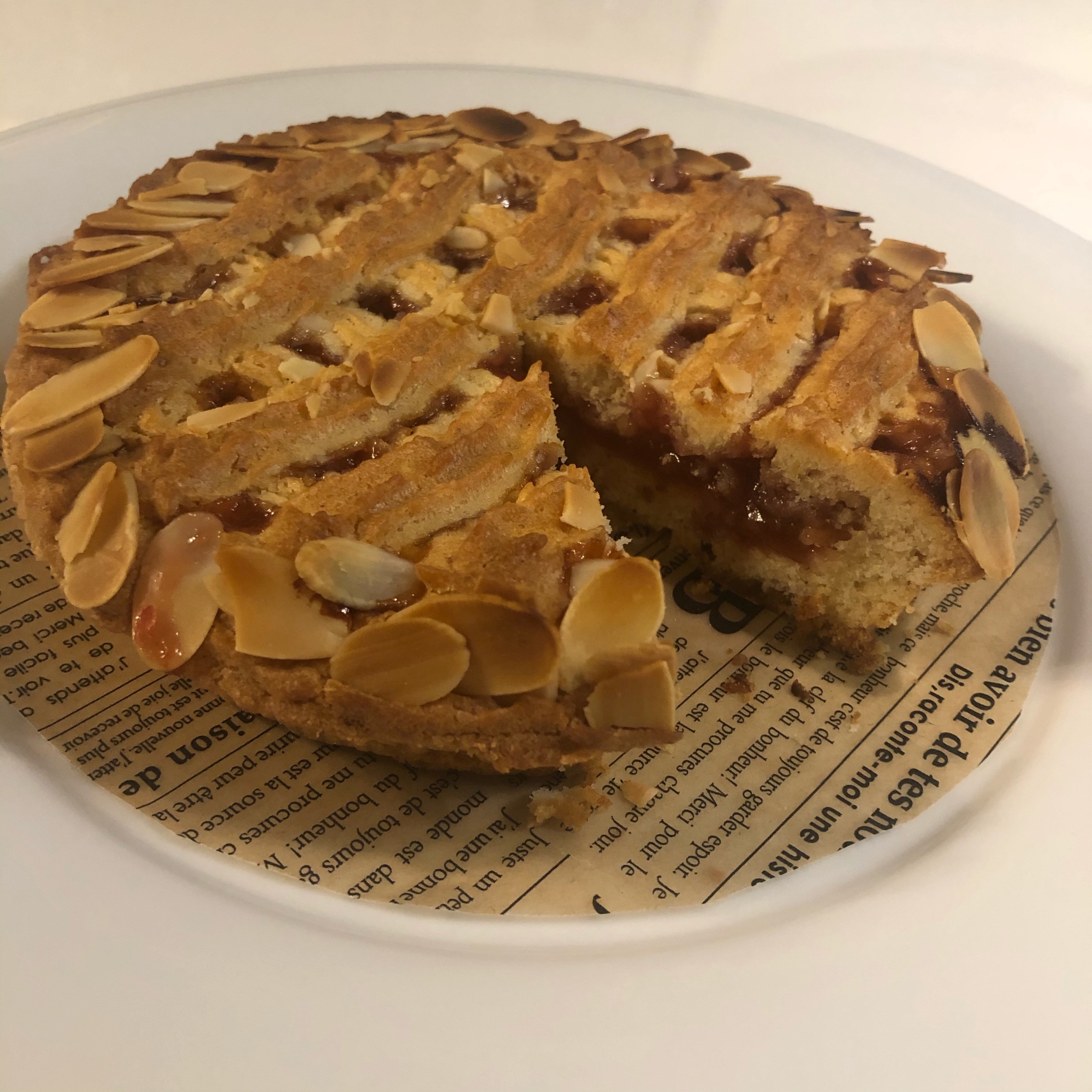 英字模様の丸い皿にのせたすもものタルト