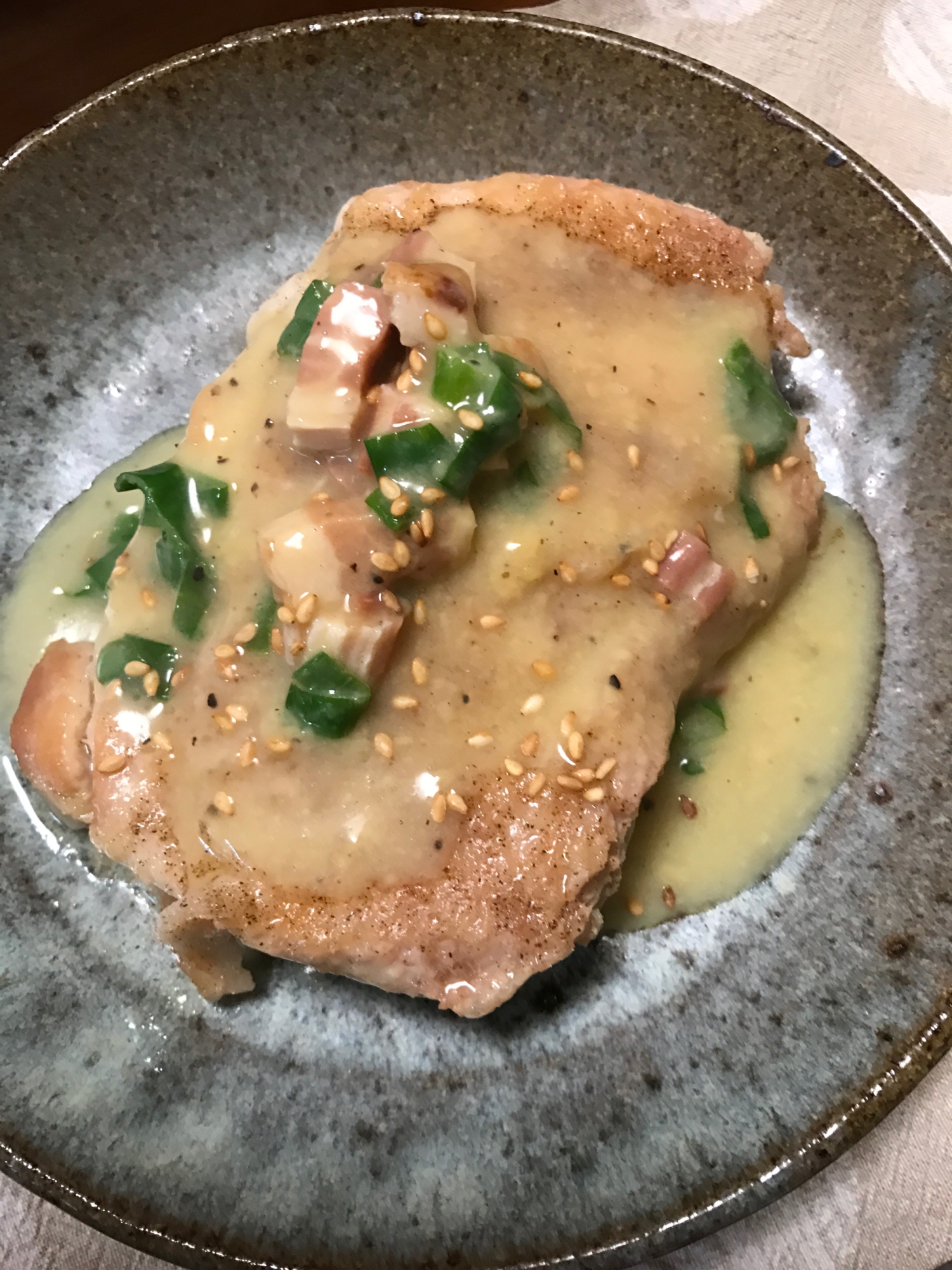 黒い皿に盛られたチキンのカルボナーラソースがけ