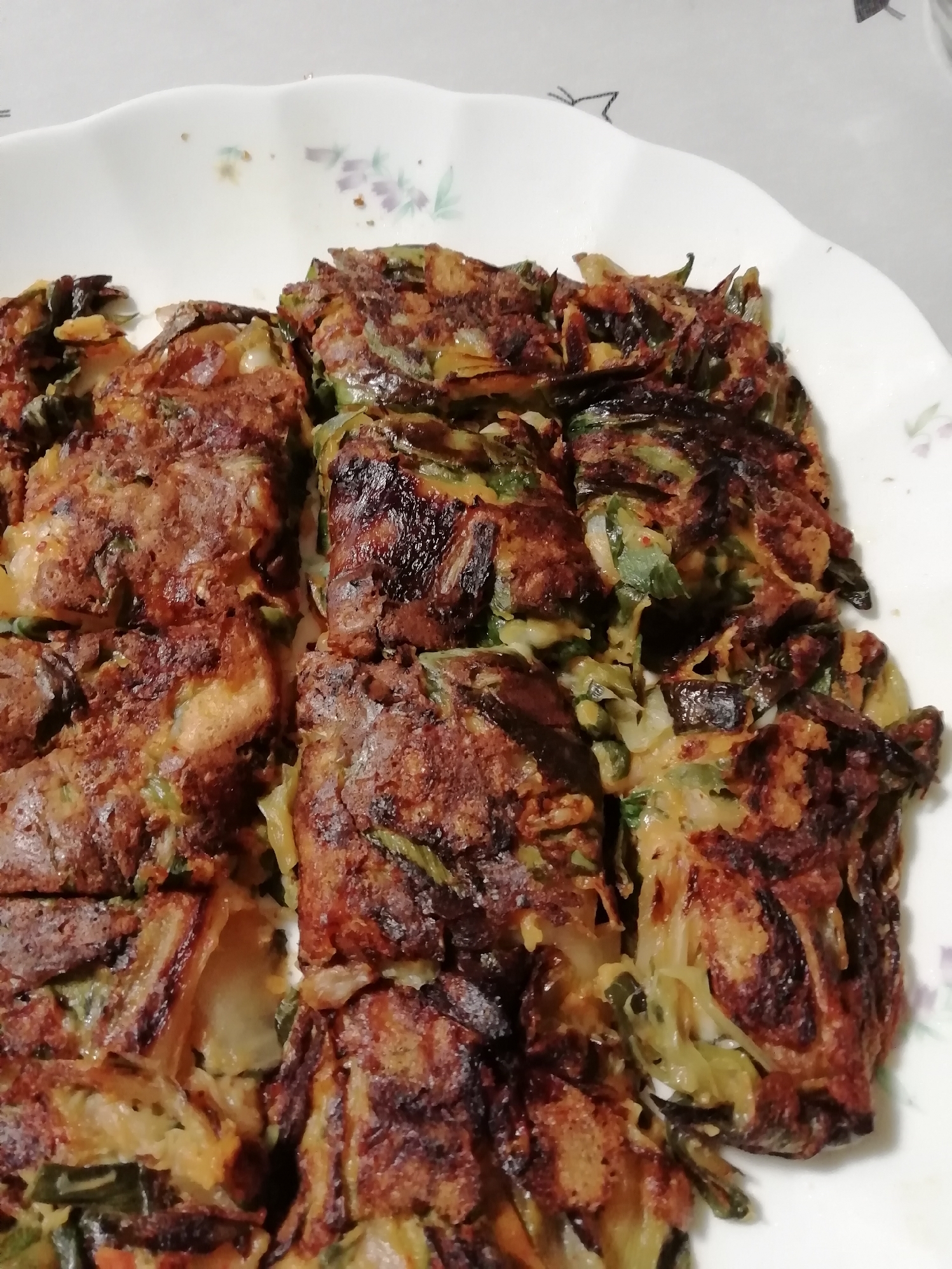 白い皿に盛られた葉玉ねぎのキムチーズチヂミ