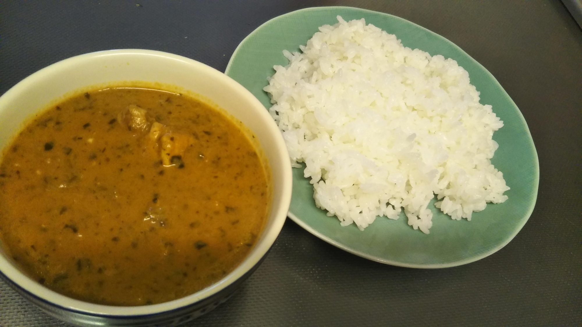 白い器に盛り付けられたキャベツサグカレー、緑のお皿に盛り付けられたご飯