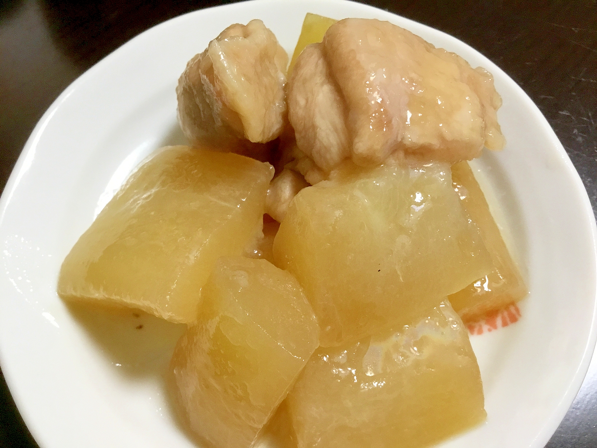 白い皿に盛り付けた夕顔と鶏肉の煮物