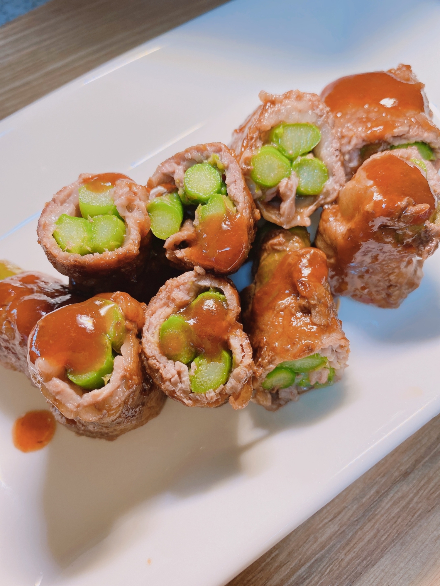 白色の長皿に盛られた冷凍アスパラの肉巻き