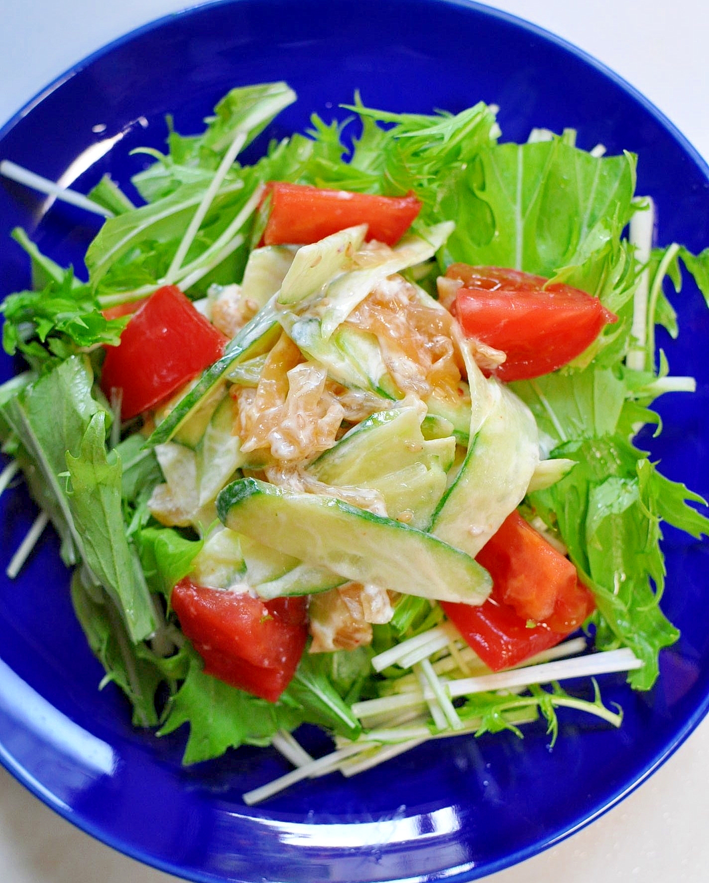 青い丸皿に盛り付けた水菜とクラゲの中華サラダ