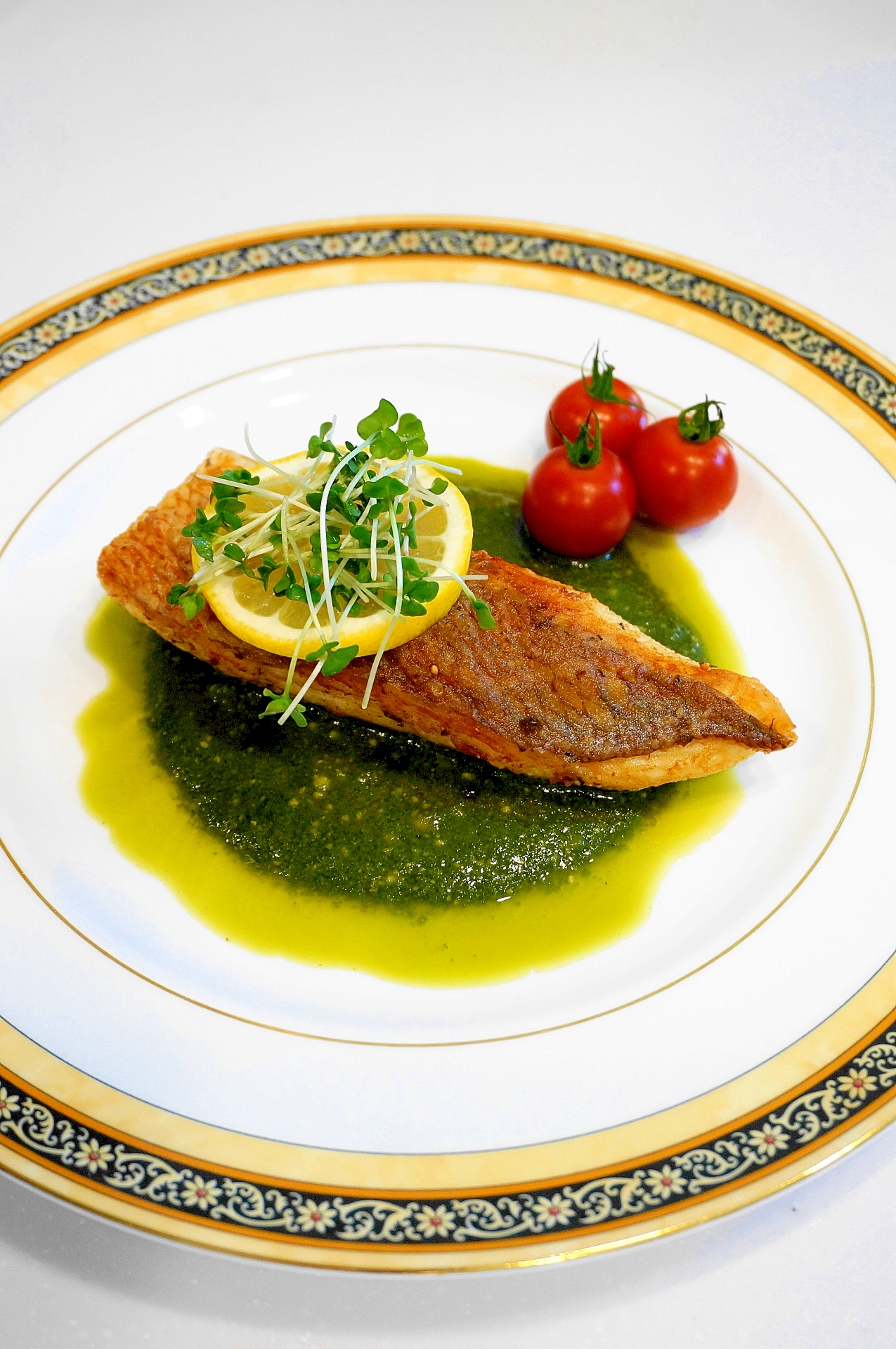 白い皿に盛られた鯛のムニエル、ジェノベーゼソース添え