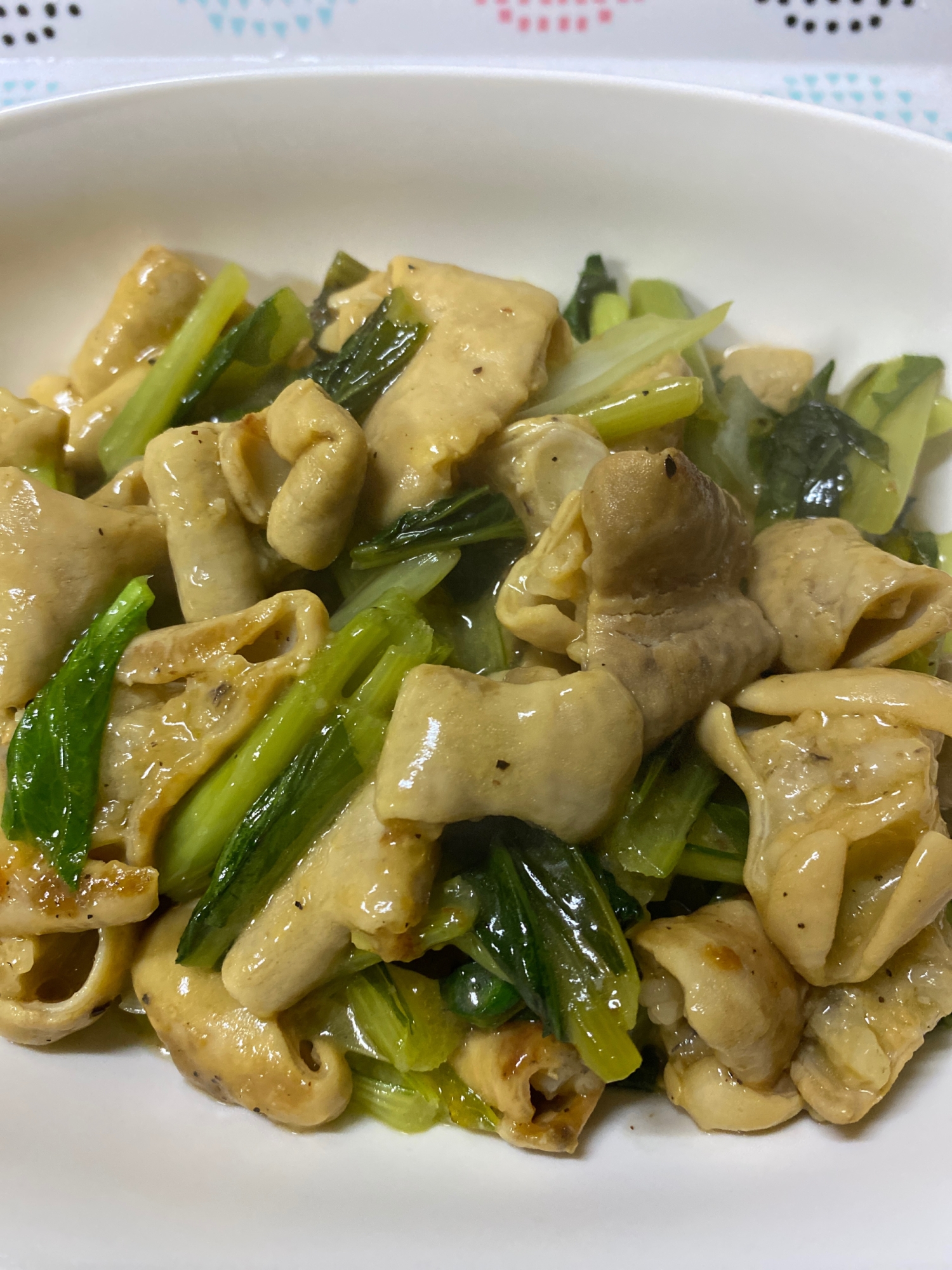 白い皿に入った牛もつと小松菜の炒め物