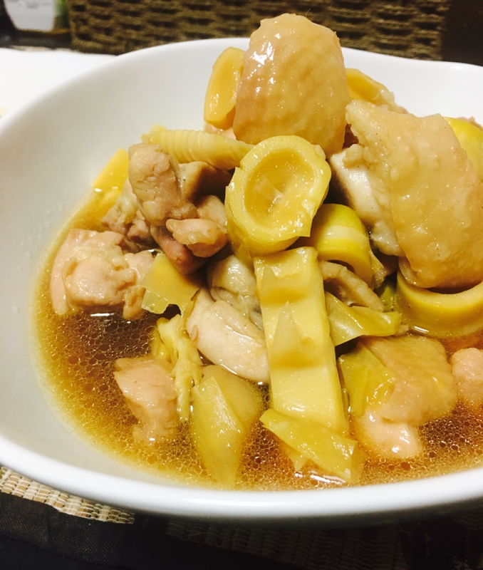 黒い皿に盛られた淡竹と鶏もも肉の煮物